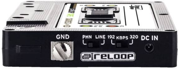 Un adaptateur de cassette audio noir avec des connexions et des boutons, le nom de marque 'Reloop' est affiché sur le devant.