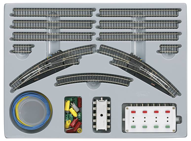 Ensemble de voies de train miniature comprenant des rails courbes et droits, des connecteurs, des fils électriques et un panneau de commande, rangé dans un plateau en plastique. Idéal pour les passionnés de modélisme ferroviaire.