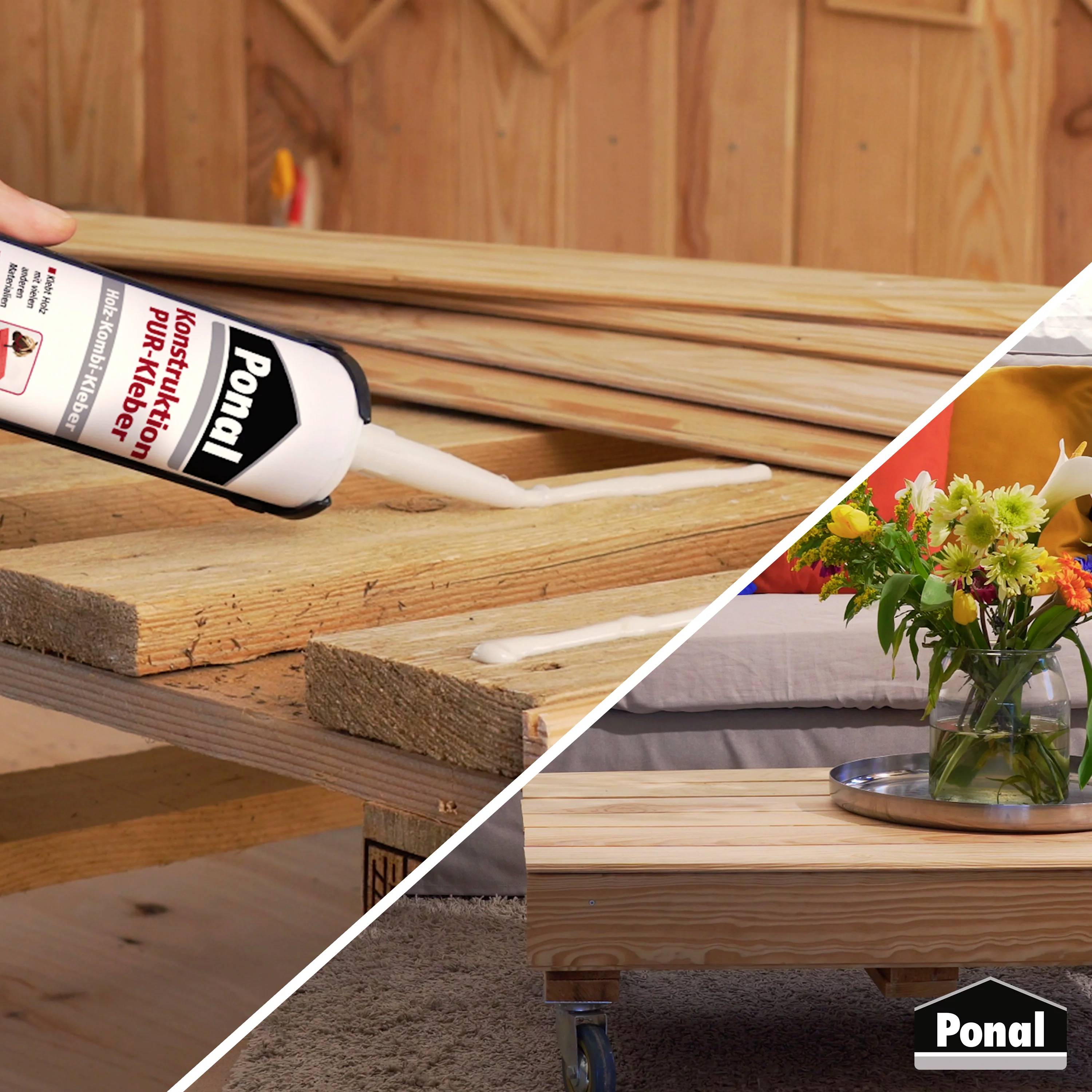 Une main applique de la colle à bois sur des planches de bois. En arrière-plan, une table avec des fleurs dans un salon.