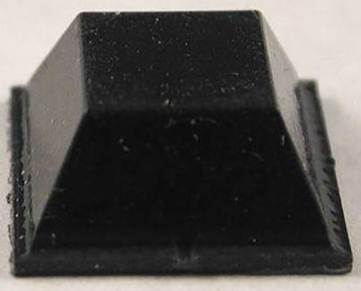 Un objet noir, carré, de forme pyramidale avec une base plate, posé sur une surface claire.