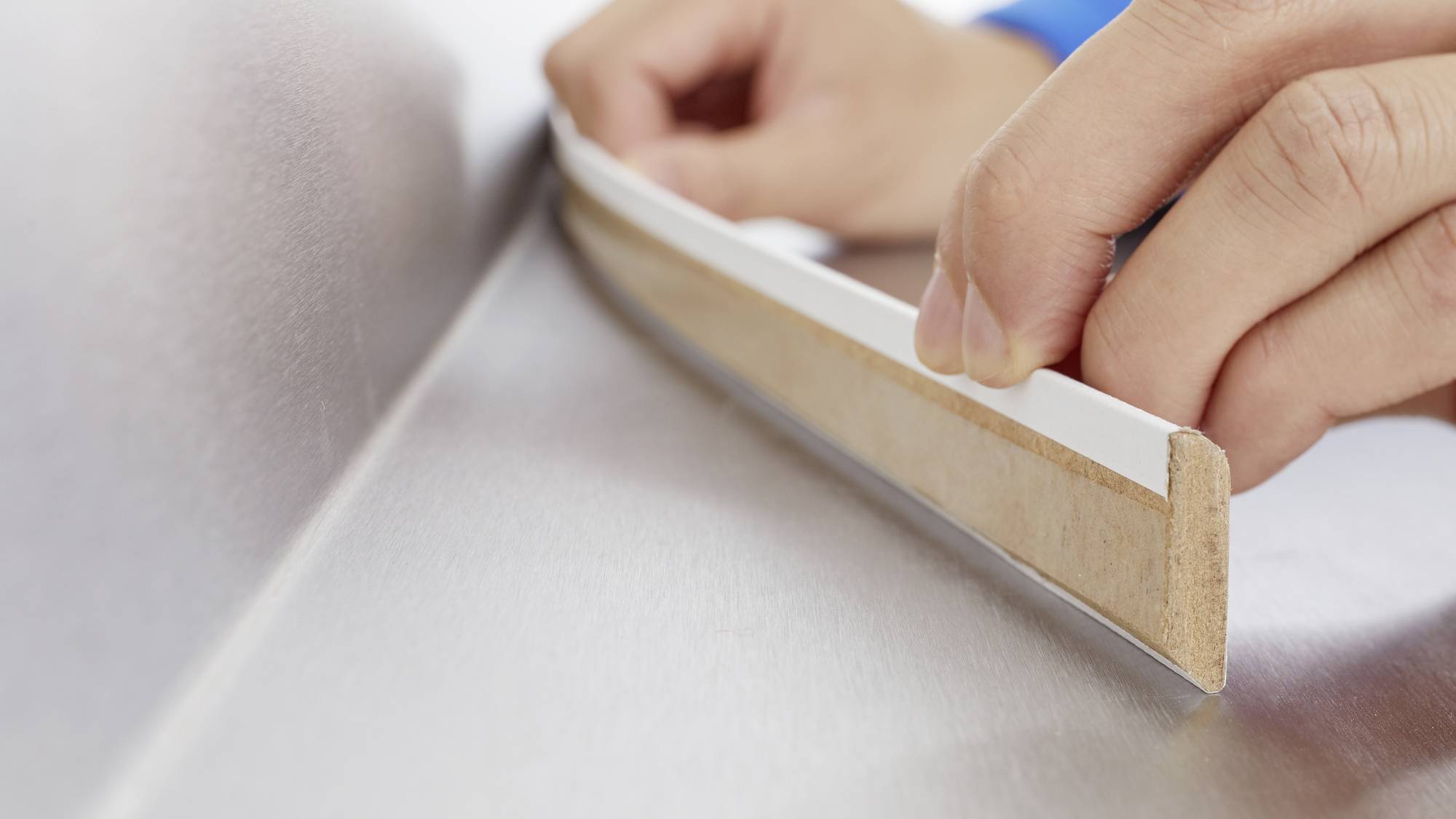 Des mains appliquent un ruban d'étanchéité autocollant sur une surface métallique afin d'assurer une étanchéité parfaite.