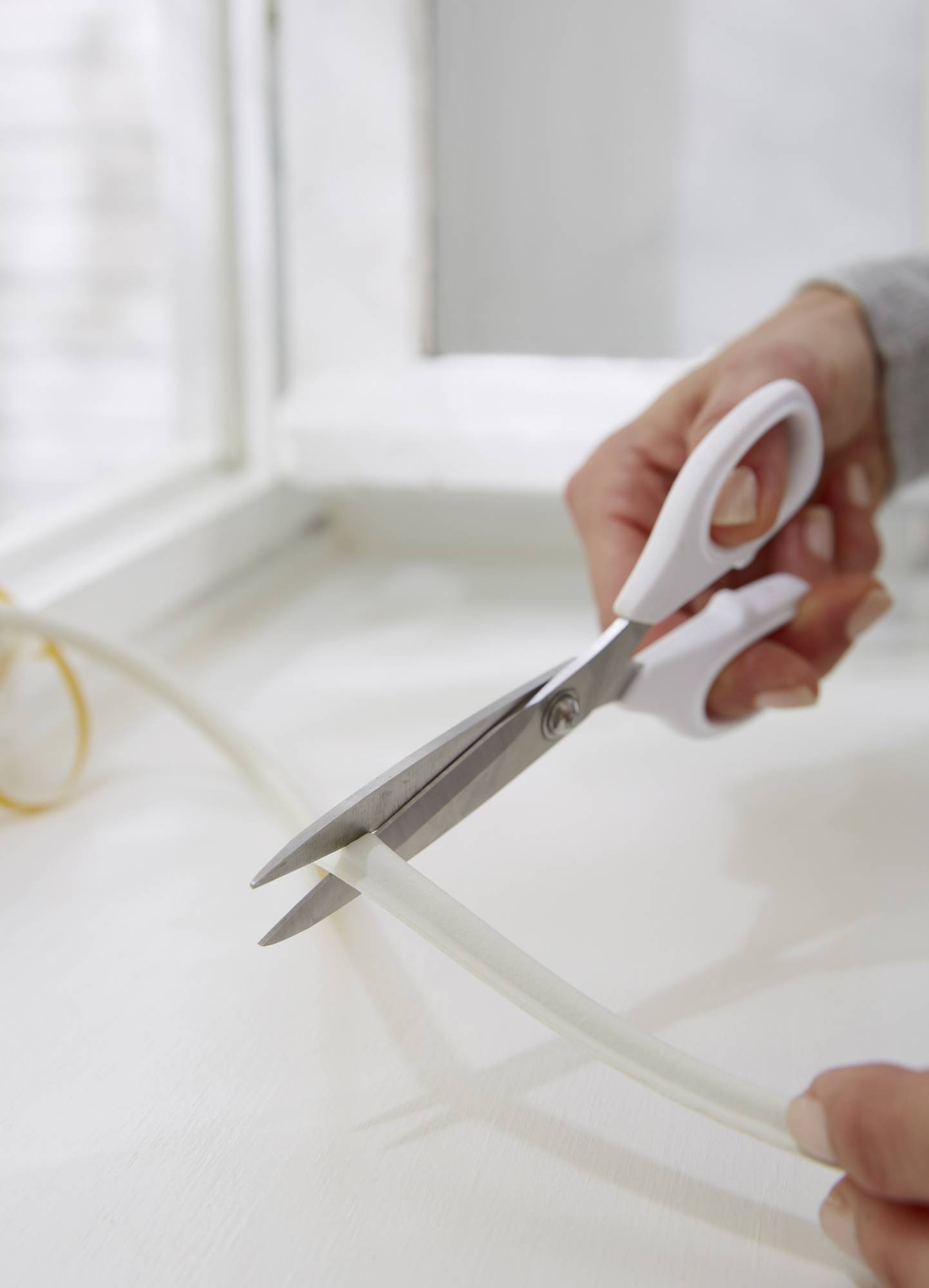 Une main coupe un câble blanc avec des ciseaux.