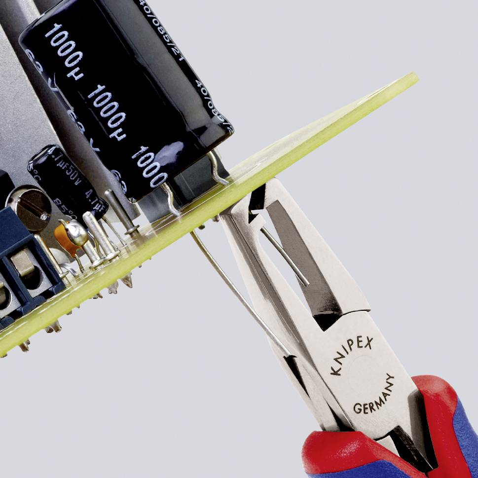 Circuit électronique avec condensateurs et microprocesseurs, tenu par une pince Knipex contre un fond gris.