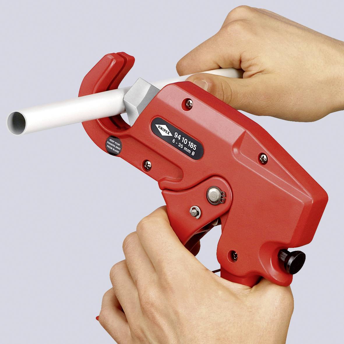 Deux mains actionnent un outil rouge qui coupe un tuyau en plastique. L'outil porte l'inscription « 94 10 185 ».