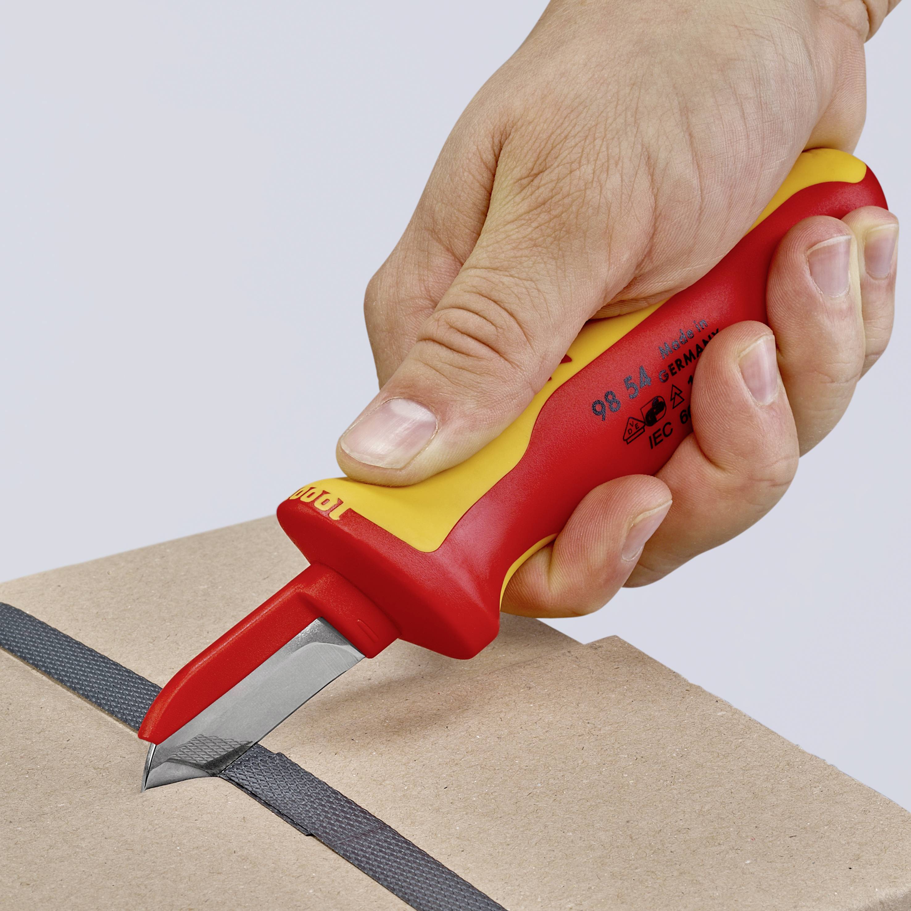 Une main tient un couteau de sécurité avec une poignée rouge et jaune. Le couteau coupe un carton le long d'une ligne noire.