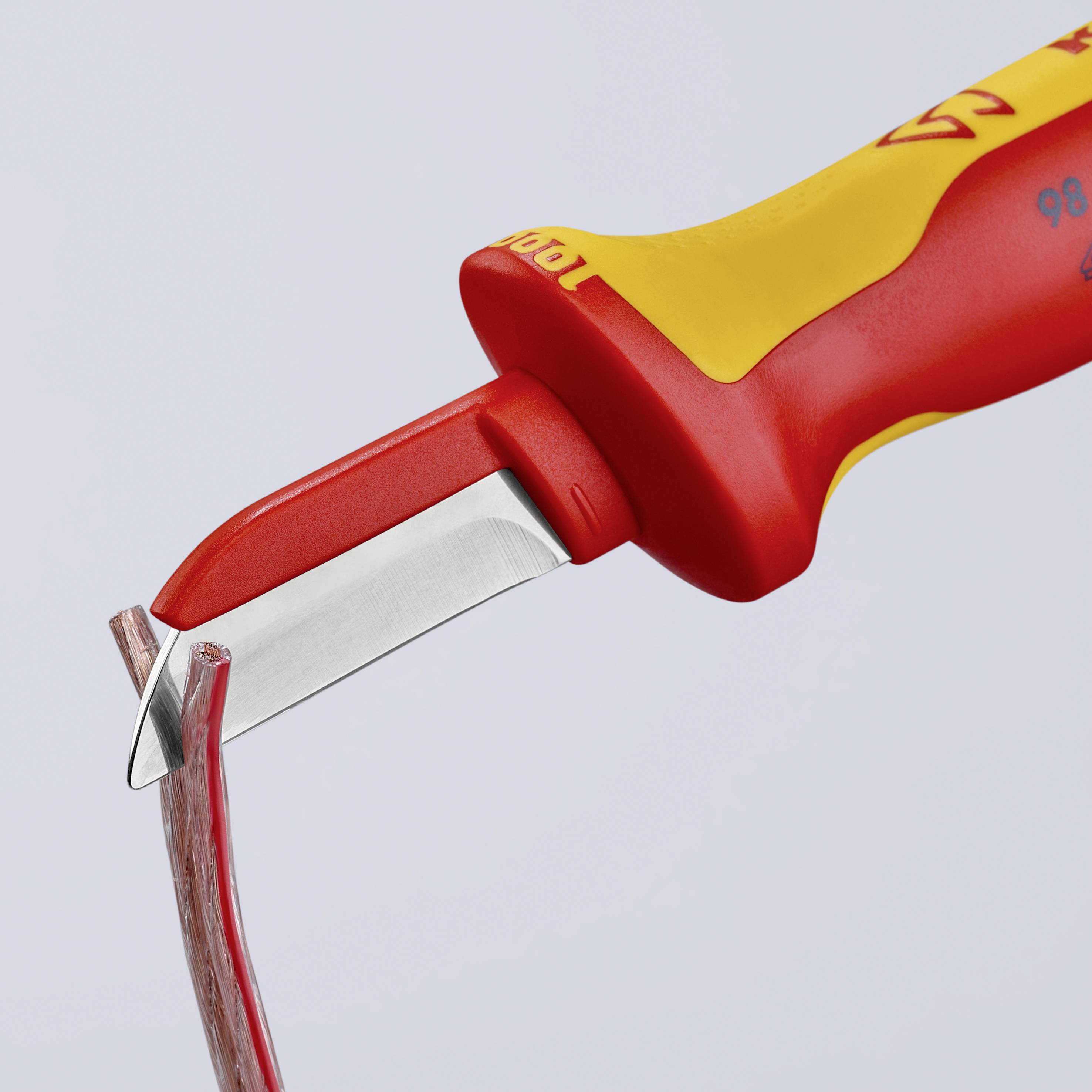 Un outil rouge et jaune coupe un câble.