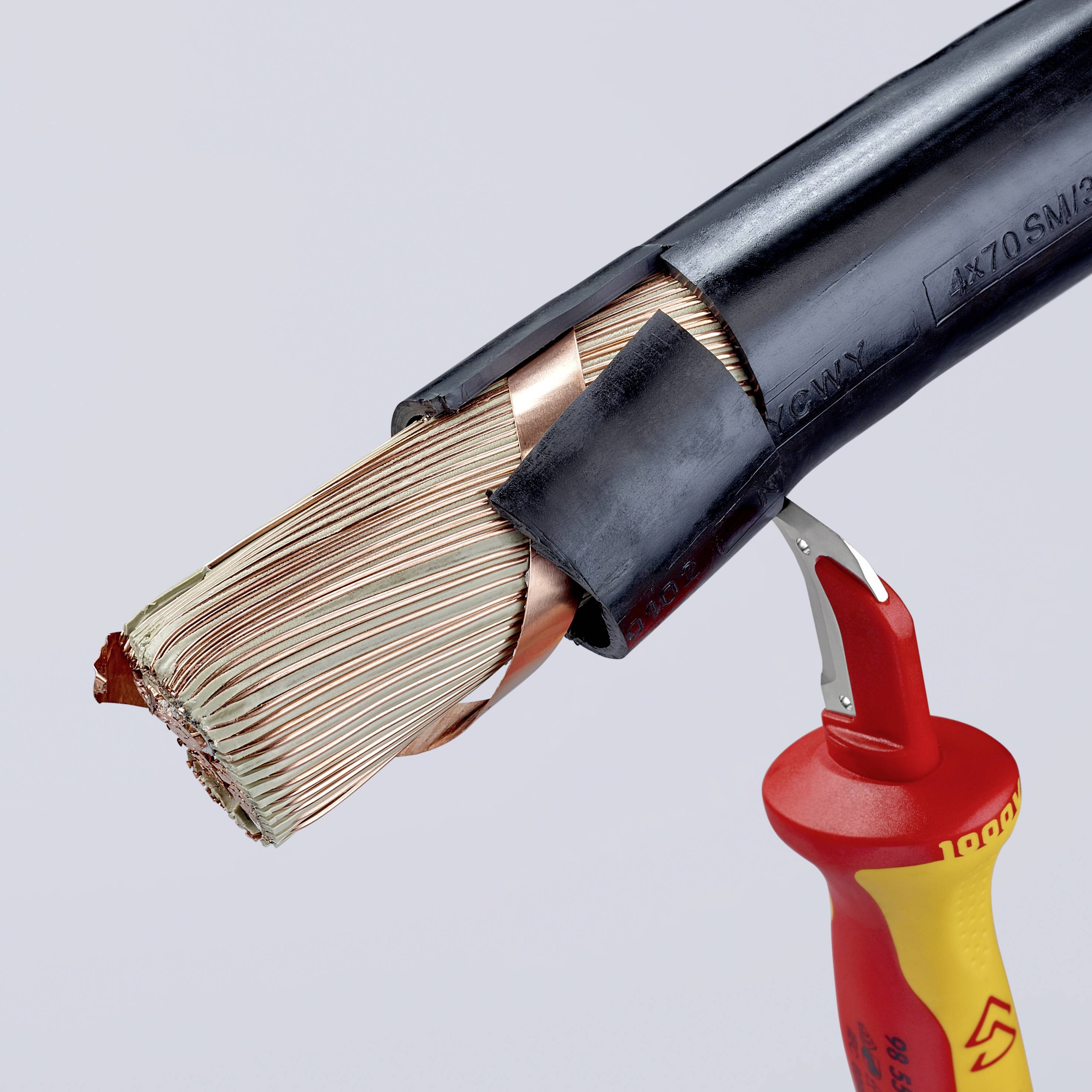Un outil rouge coupe un épais câble électrique noir avec des fils de cuivre dénudés.