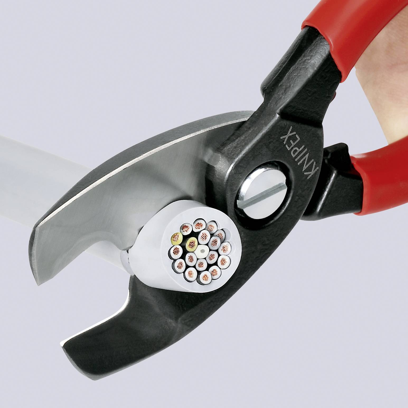Gros plan d'un coupe-câble rouge coupant un câble. La surface de coupe montre un faisceau de fils en coupe transversale.