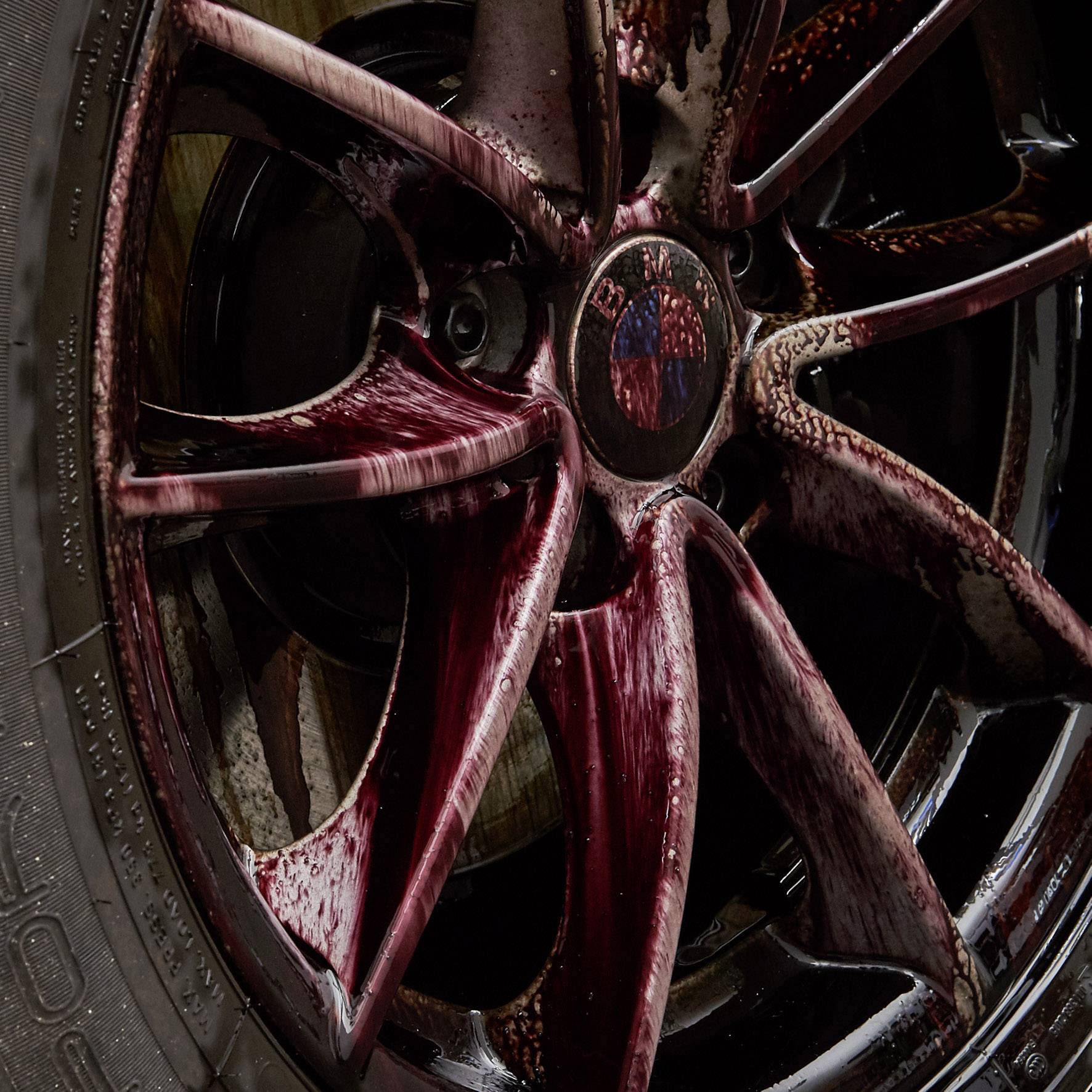 Gros plan sur un pneu de voiture avec sa jante. La jante présente une coloration rouge-brun, probablement due à la poussière de frein ou à des salissures.