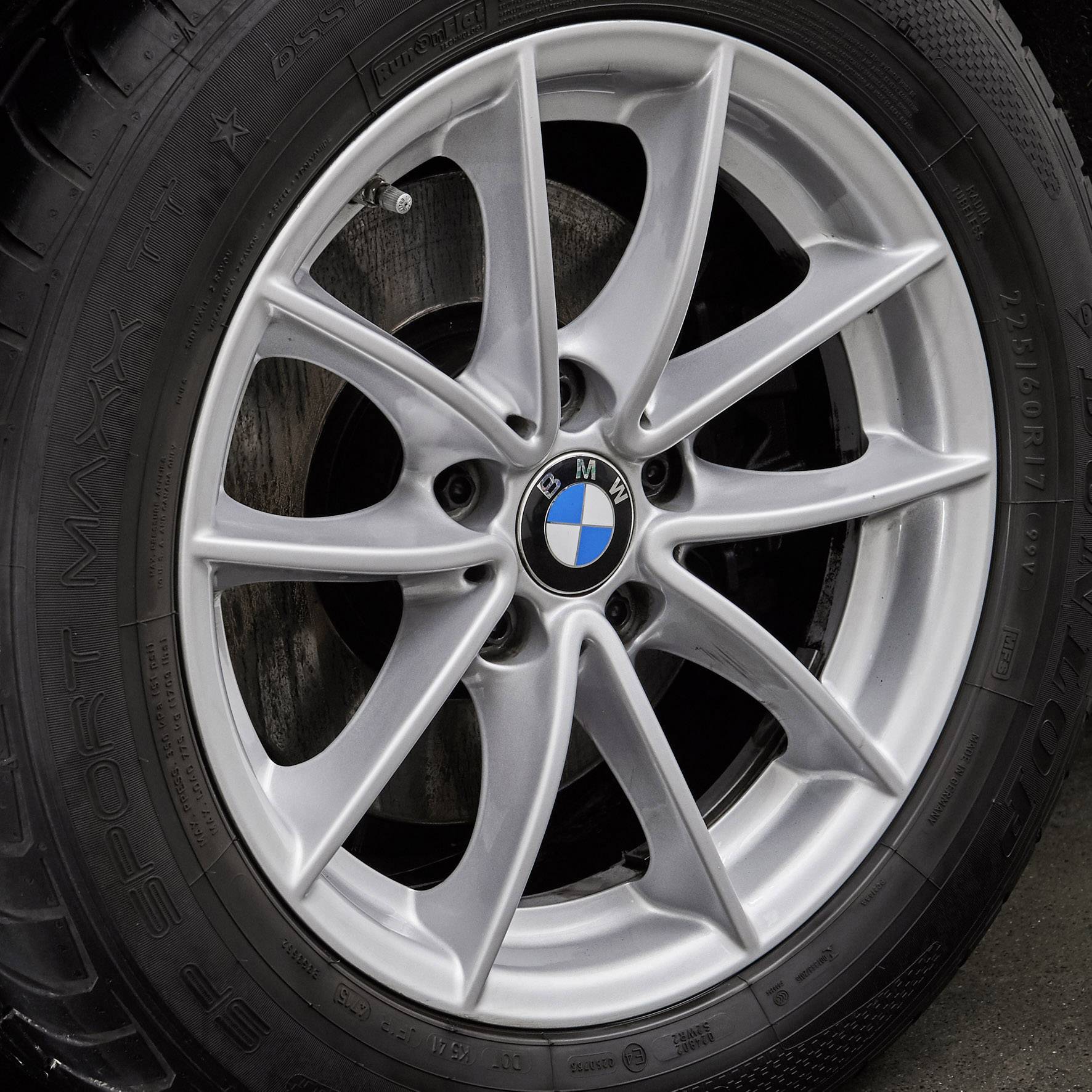 Gros plan d'un pneu de voiture BMW argenté avec le logo bleu et blanc sur la jante, monté sur un véhicule.