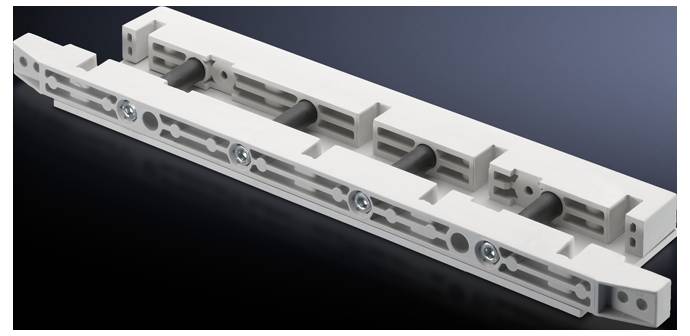 Longue pièce rectangulaire en plastique avec plusieurs entailles et vis, sur un fond sombre. Utilisable dans des appareils techniques.