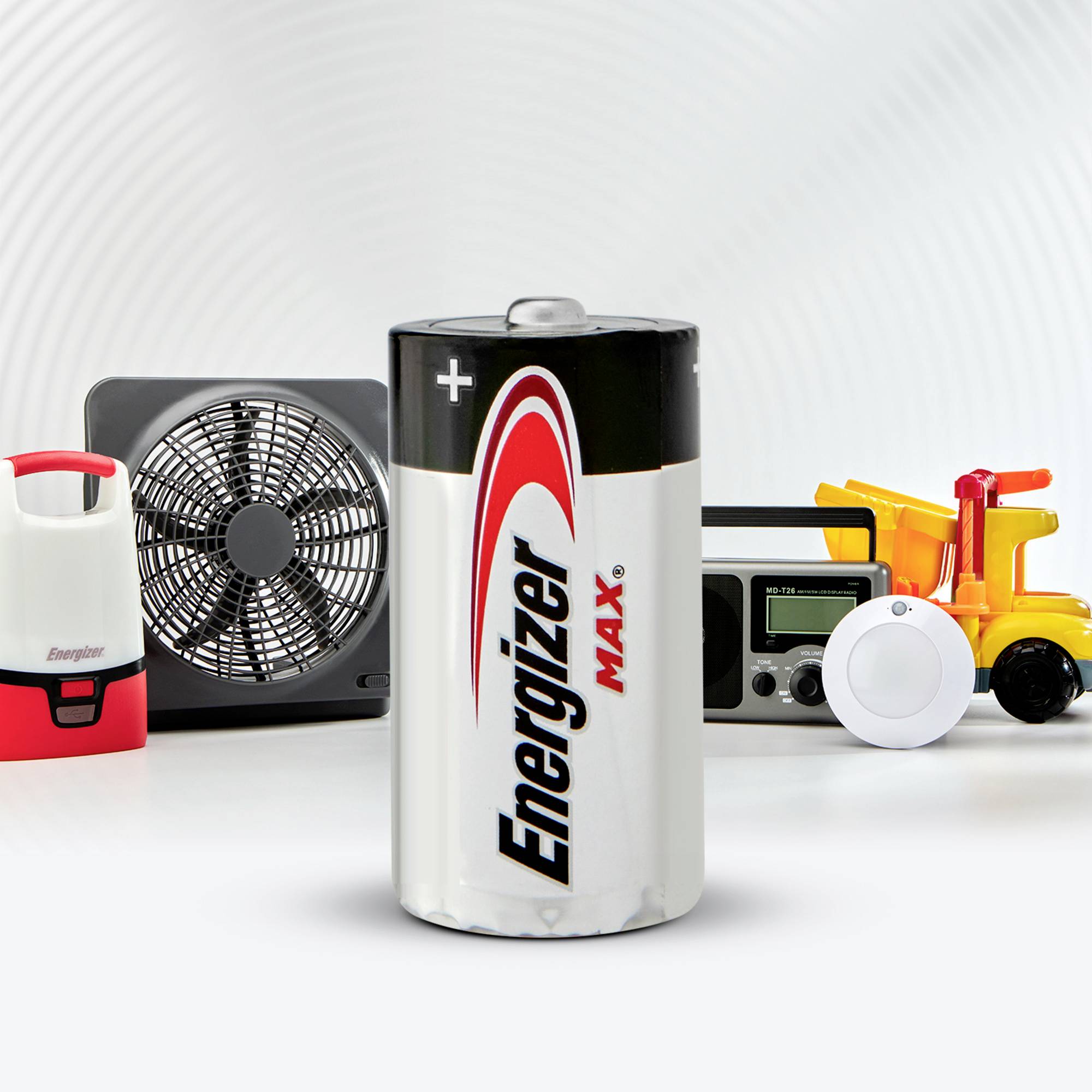 Une pile Energizer au premier plan avec d'autres appareils électroménagers en arrière-plan, dont un ventilateur, une radio et une lampe.