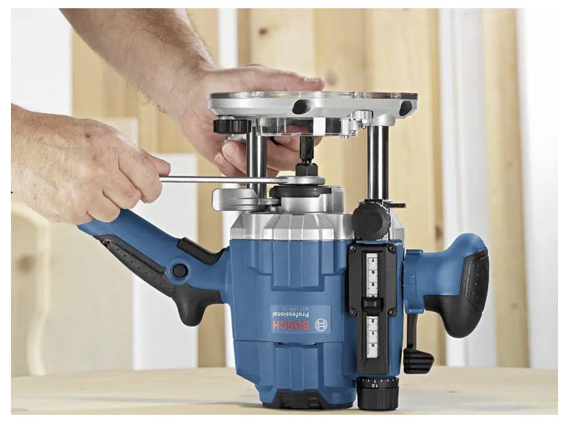 Hands using a Bosch router mounted in a plunge router table for woodworking on a wooden workbench.