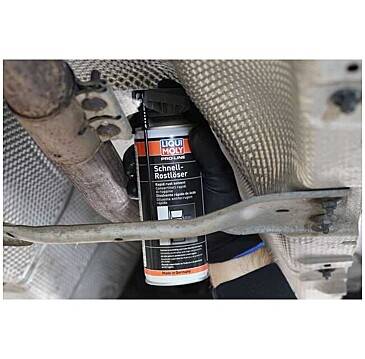 « Liqui Moly Schnell-Rostlöser » peut être vaporisé par une main gantée sur une pièce métallique sous un véhicule, possiblement pour l'élimination de la rouille.