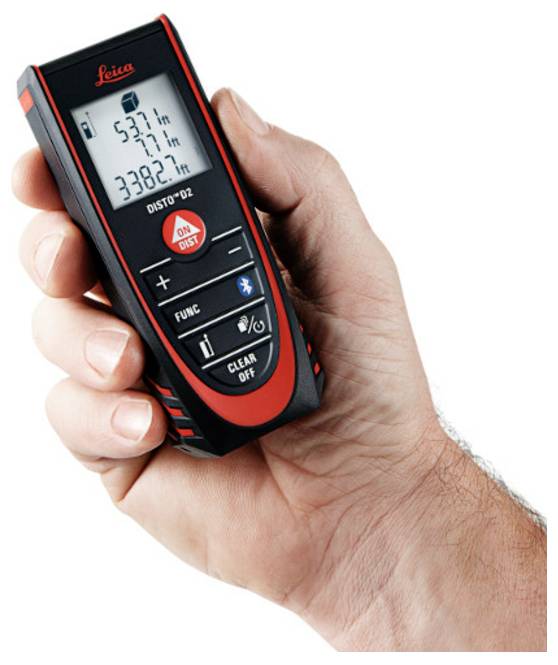 Une main tenant un télémètre laser Leica DISTO D2 rouge et noir affichant trois mesures en mètres sur l'écran.
