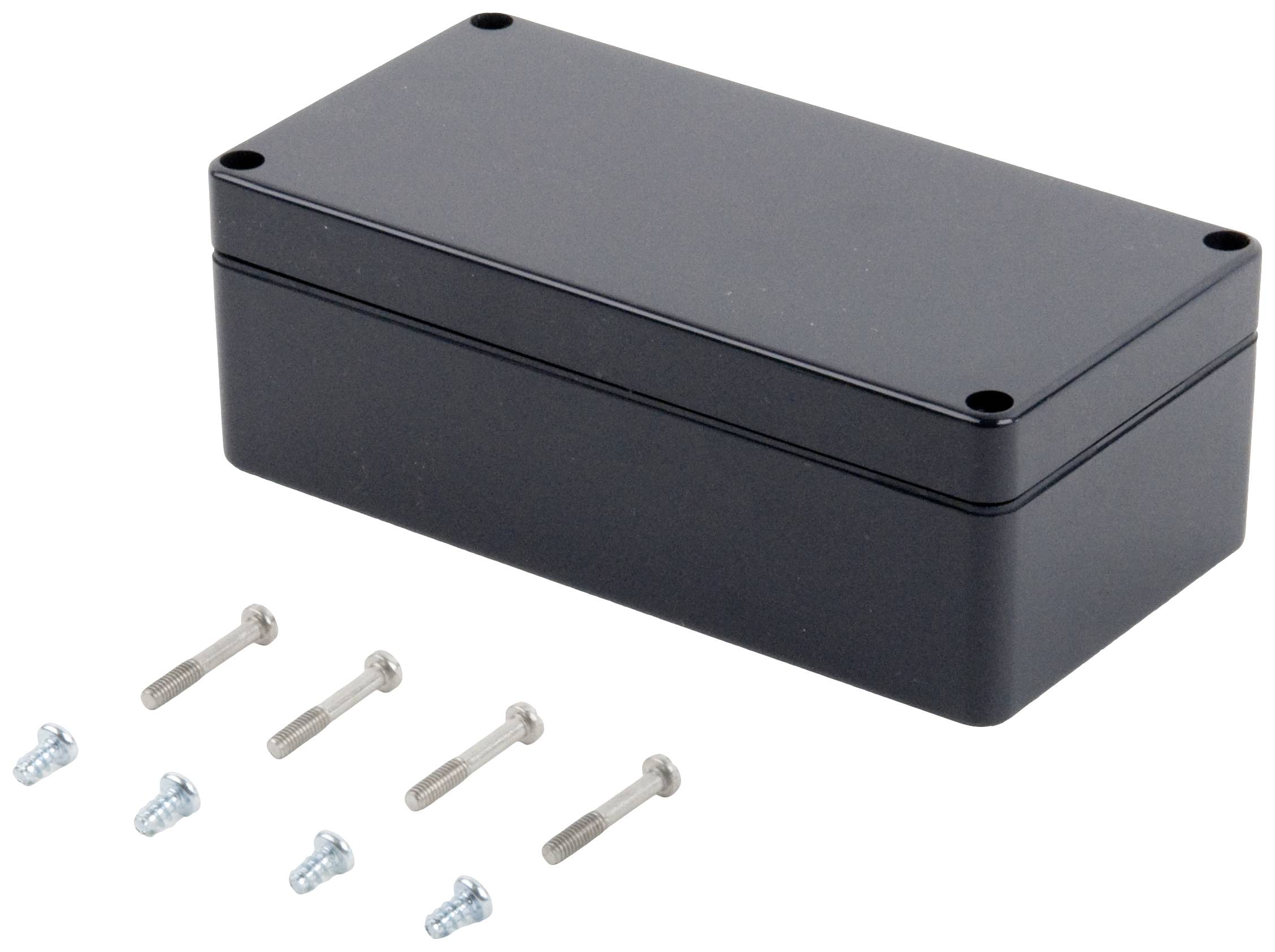 Boîtier rectangulaire noir à quatre coins. Six vis de deux tailles différentes sont disposées à sa gauche.
