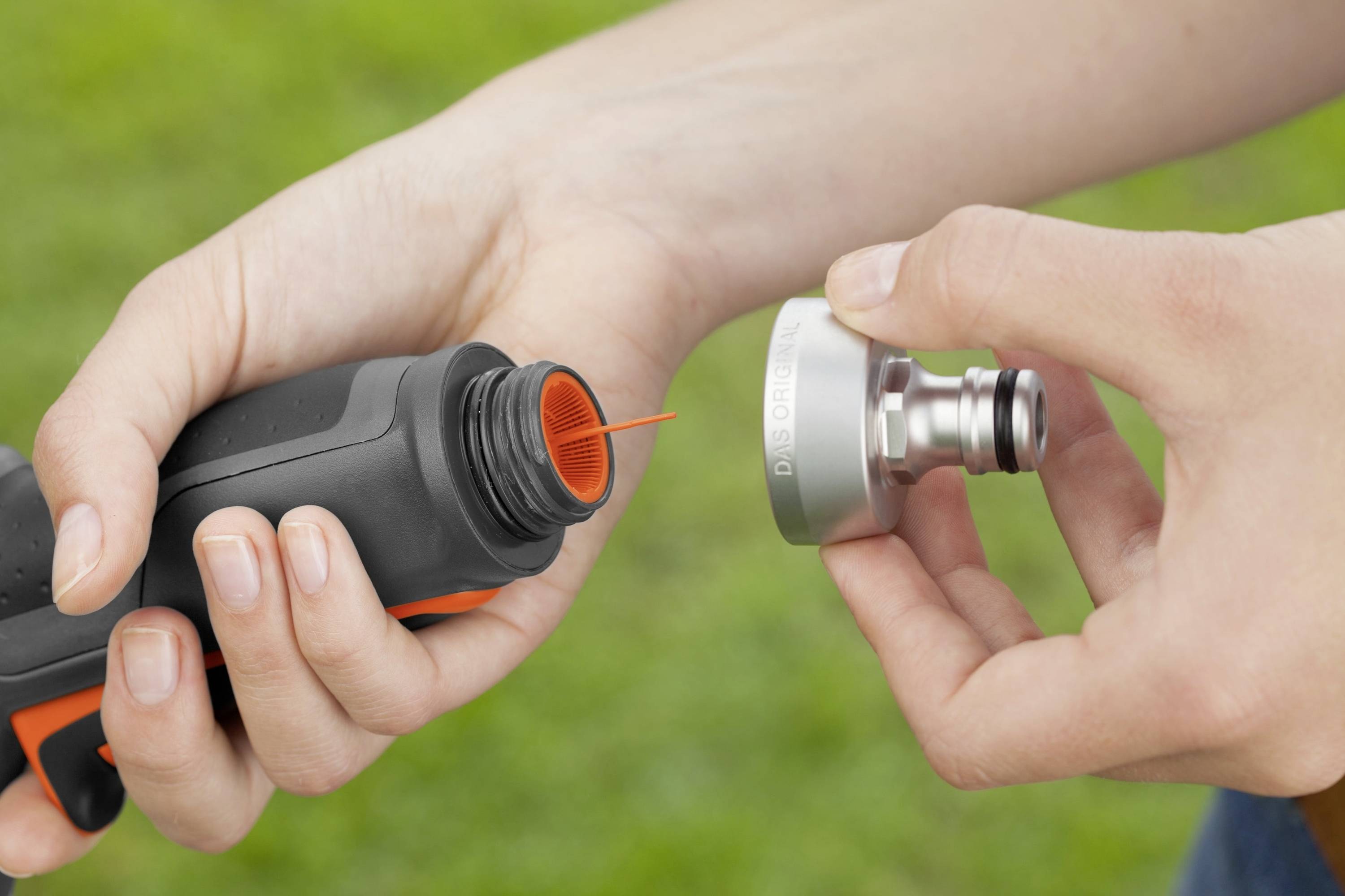 Une personne tient des pièces d'équipement dans ses mains. À gauche, un objet noir ressemblant à une bouteille avec un embout orange, à droite une valve métallique.