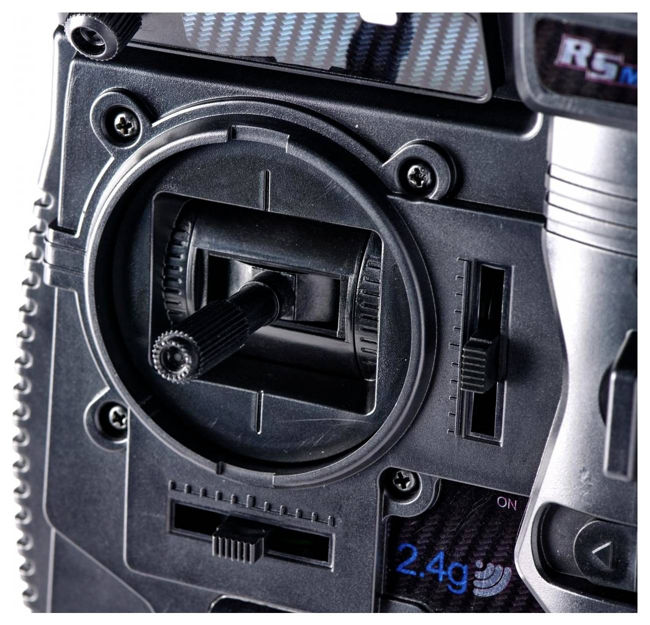 A close-up of a radio control transmitter joystick, showing a circular base, vertical sliders, and a knob, with '2.4g' text visible.