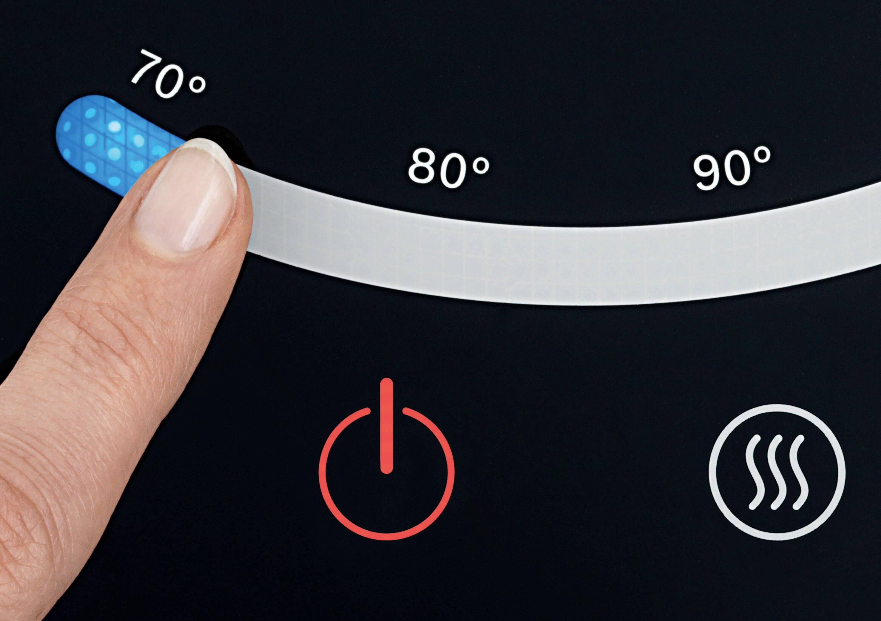 Un doigt tourne le bouton du thermostat numérique à 70 degrés. Un symbole rouge signale que l'appareil est en marche.