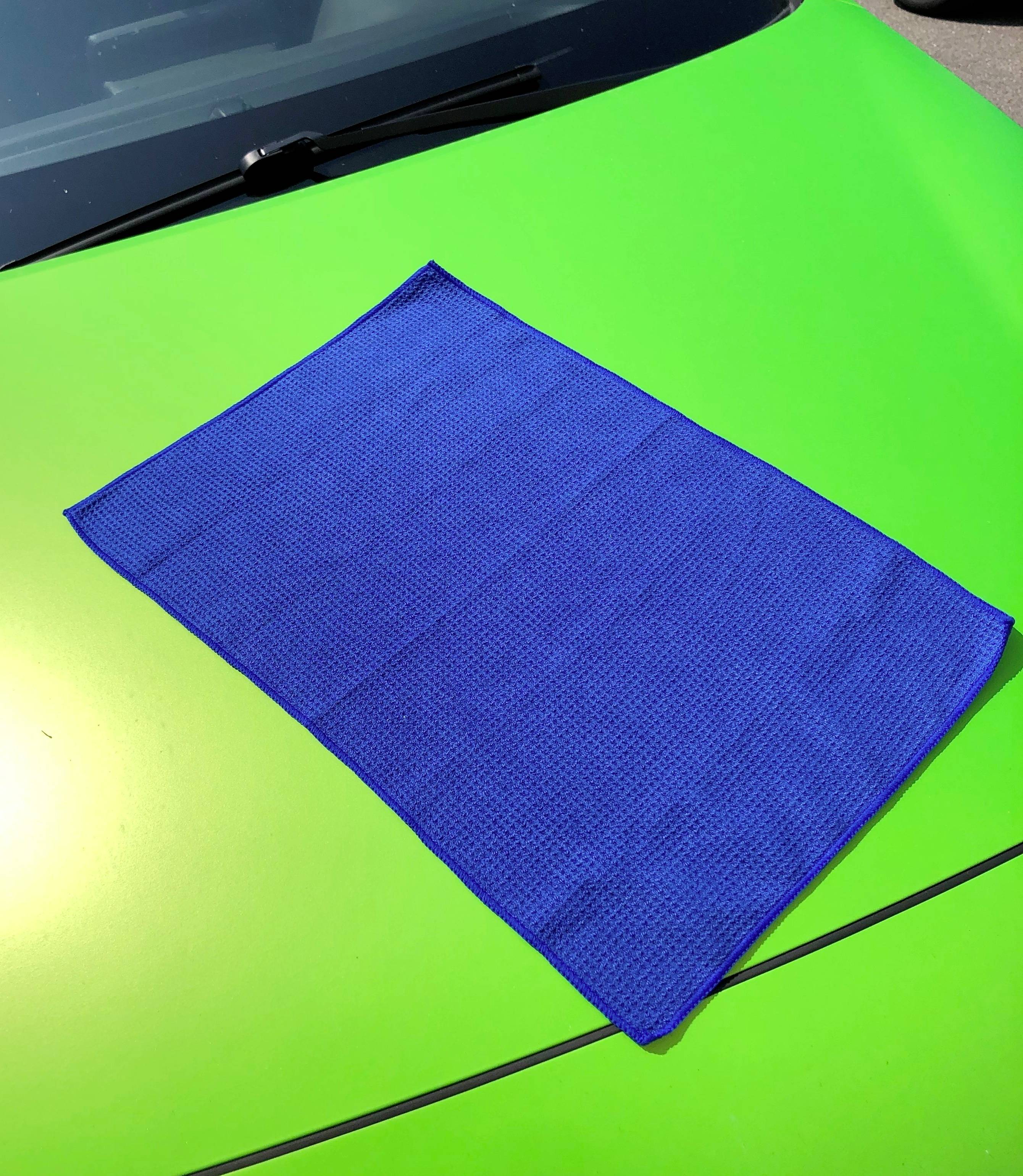 Un chiffon bleu est posé sur le capot d'une voiture verte.