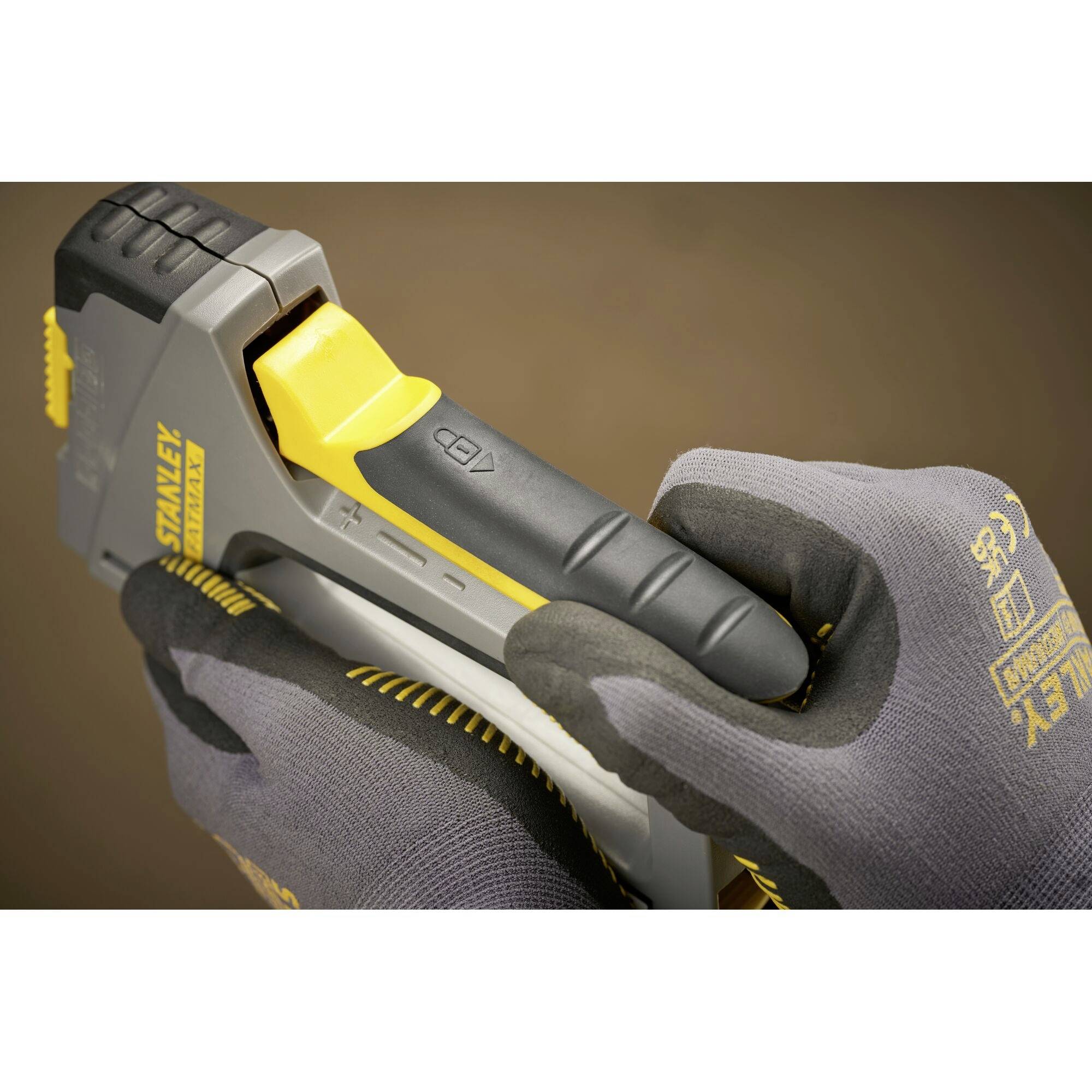 Des mains humaines gantées tiennent et utilisent un pistolet à agrafes utilisé pour des travaux de construction ou de bricolage.
