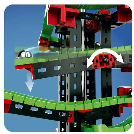 Gros plan sur un système de construction modulaire avec des éléments de construction noirs, verts et rouges. Une bille métallique descend le long d'un rail incurvé.