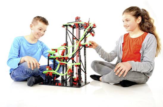 Deux enfants jouent avec un circuit de train de construction. Ils assemblent des parties du circuit et semblent prendre beaucoup de plaisir.