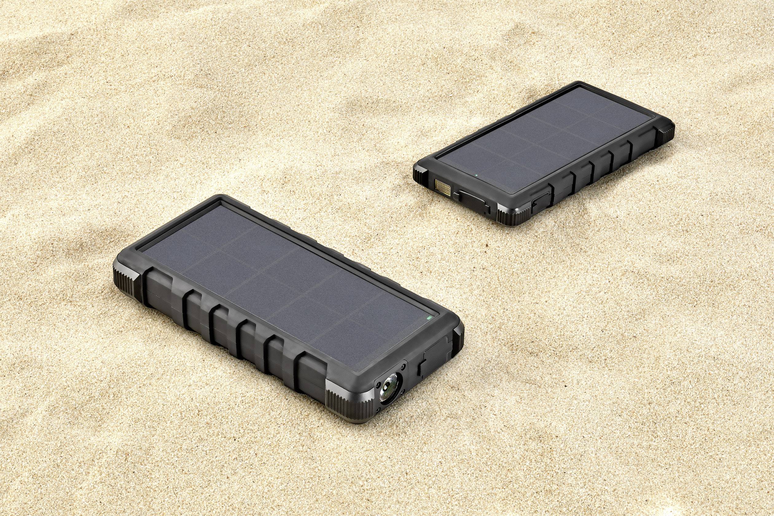 Deux panneaux solaires portables sont posés sur le sable. Ils sont rectangulaires et ont un design robuste, adaptés à une utilisation en extérieur.