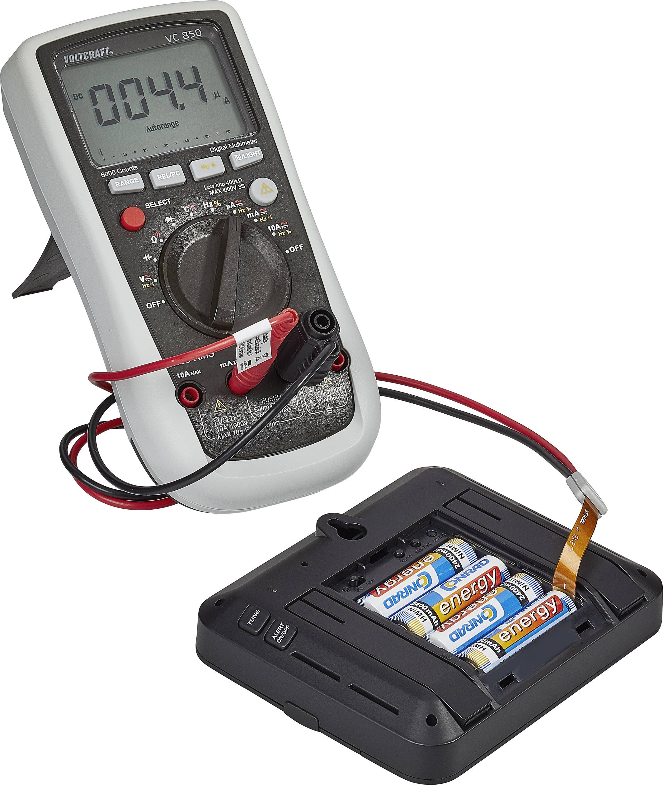Un multimètre mesure la tension de quatre piles AA dans un support. L'affichage indique '0,044 V'. Les sondes de test sont connectées aux batteries.