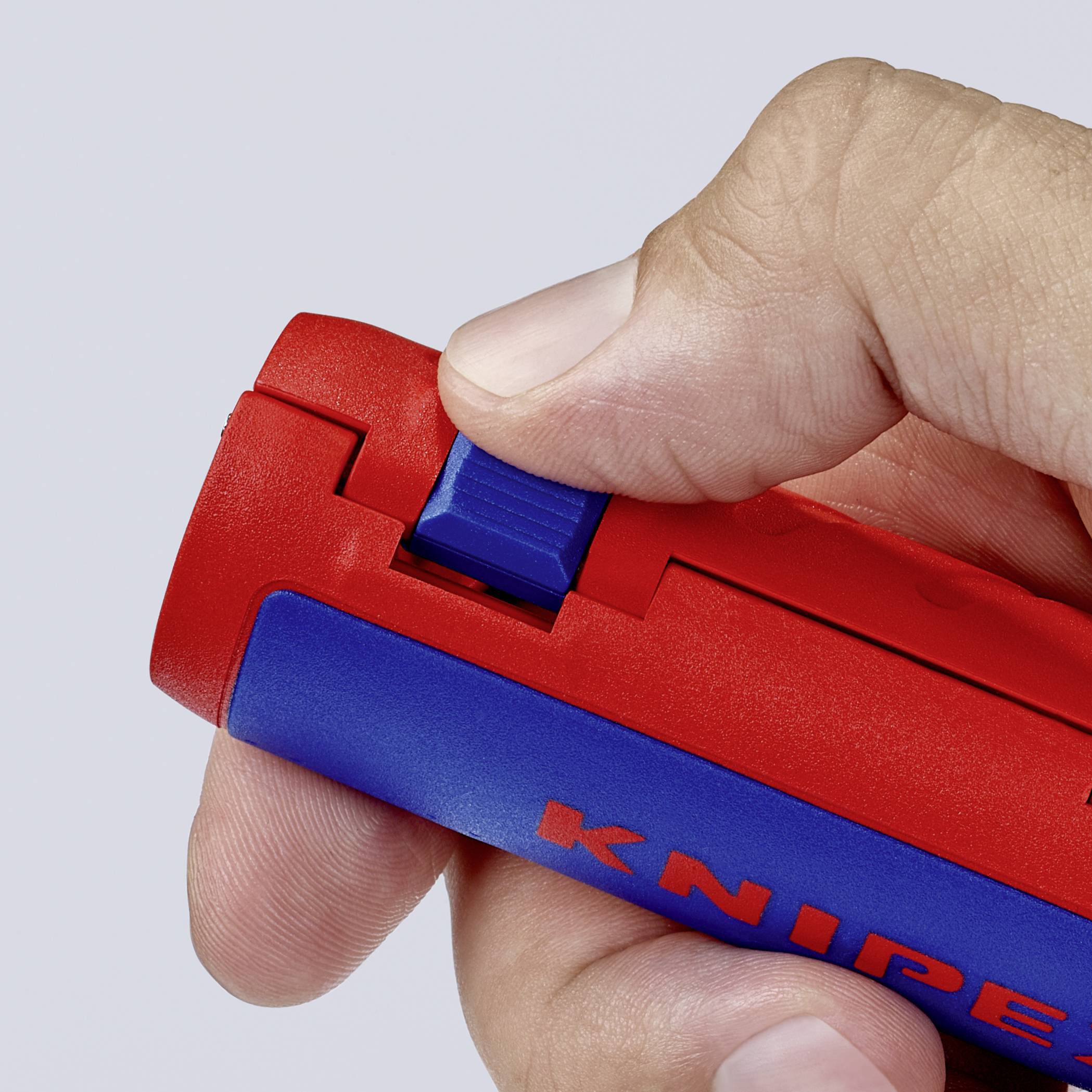 Une main tient un dénudeur de câbles rouge et bleu de Knipex. Le pouce appuie sur le curseur bleu.