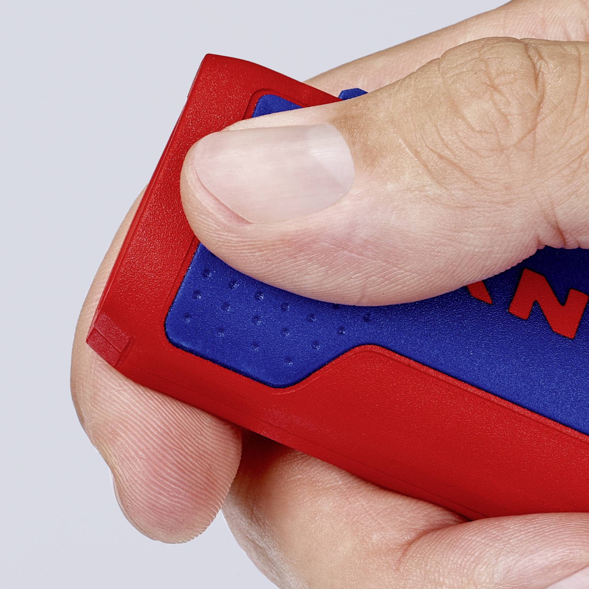 Une main tient un objet bleu et rouge qui ressemble à un boîtier.