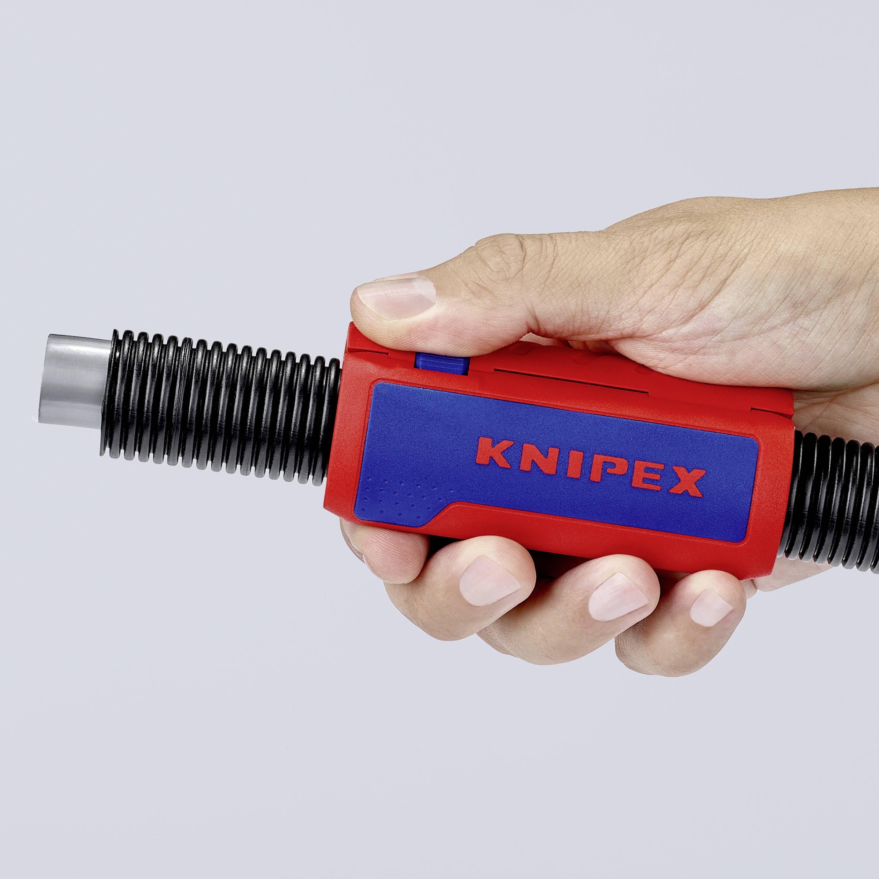 Une main tient un outil KNIPEX, rouge et bleu, avec des extrémités striées noires. L'outil est fermé.