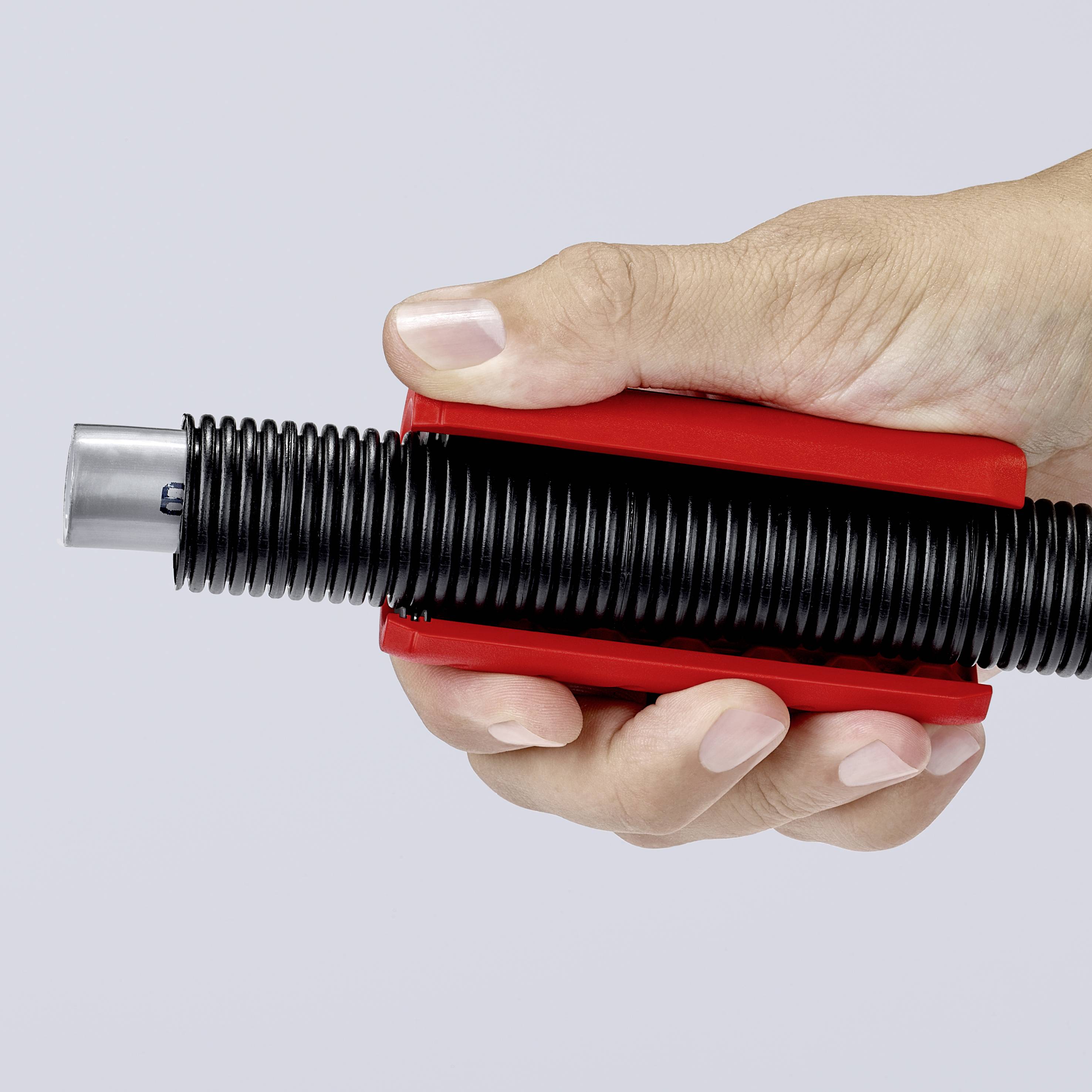 Une main tient fermement un stylo à encre rouge et noir.