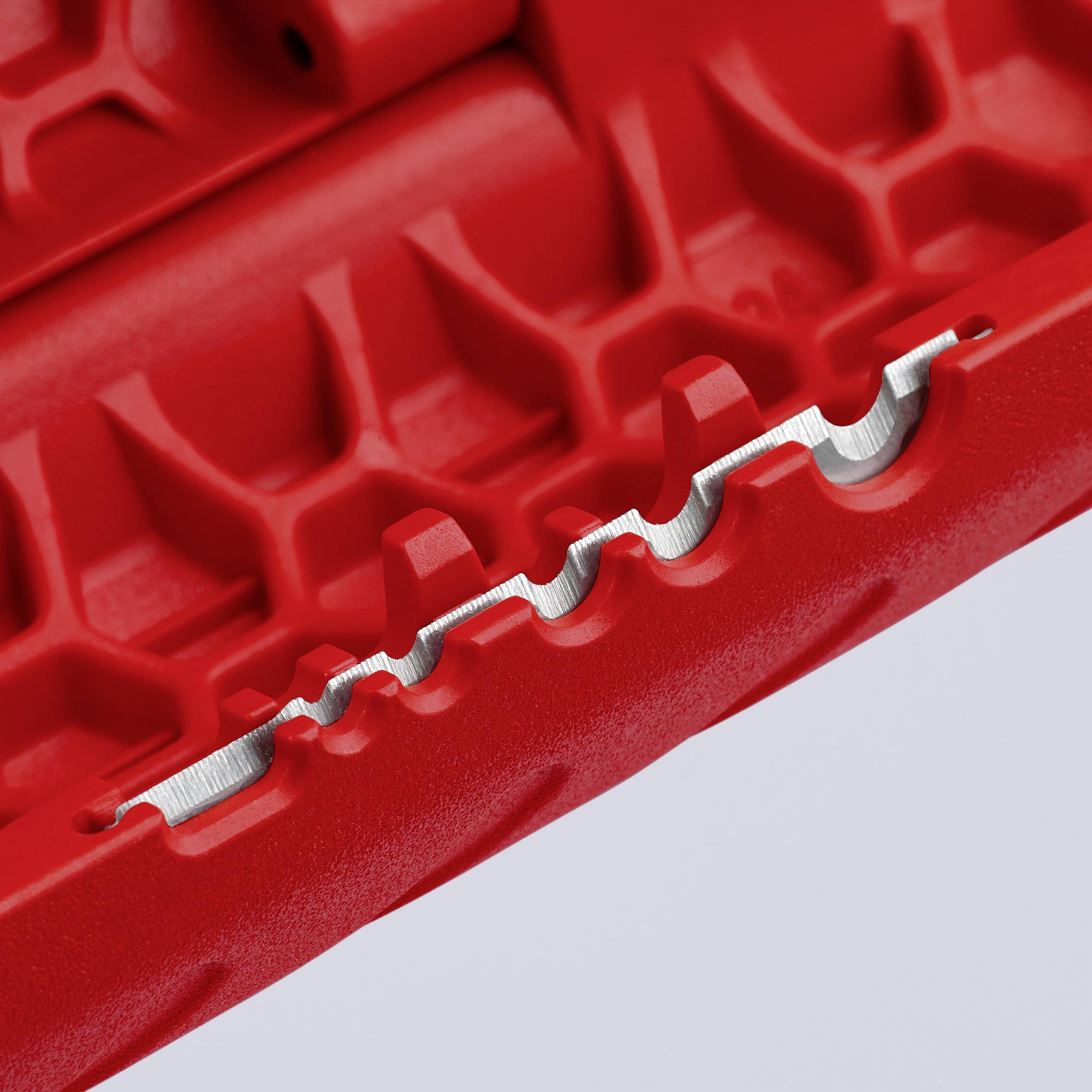 Gros plan d'une surface rouge texturée avec un bord métallique ondulé, révélant un objet technique.