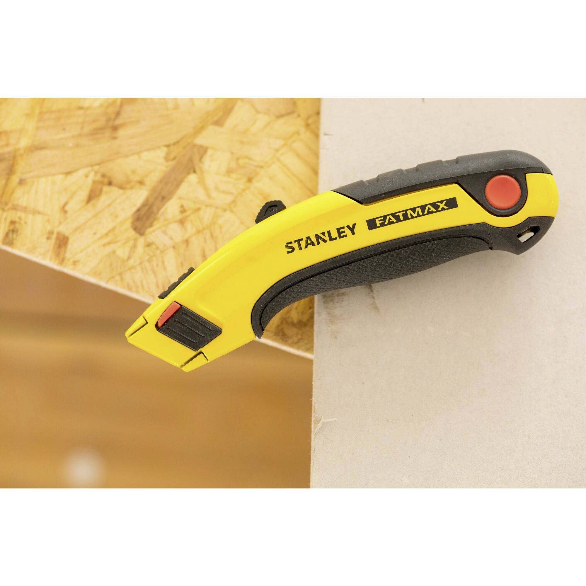 Un couteau universel jaune Stanley Fatmax repose sur une planche en bois ; design ergonomique, utilisé pour les travaux de coupe.