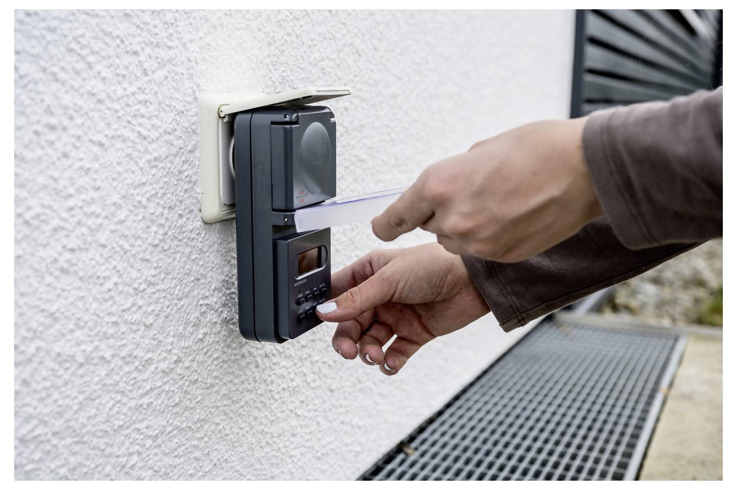 Une personne glisse une carte sur un clavier de contrôle d'accès monté à l'extérieur d'un mur pour déverrouiller une porte ou un portail.