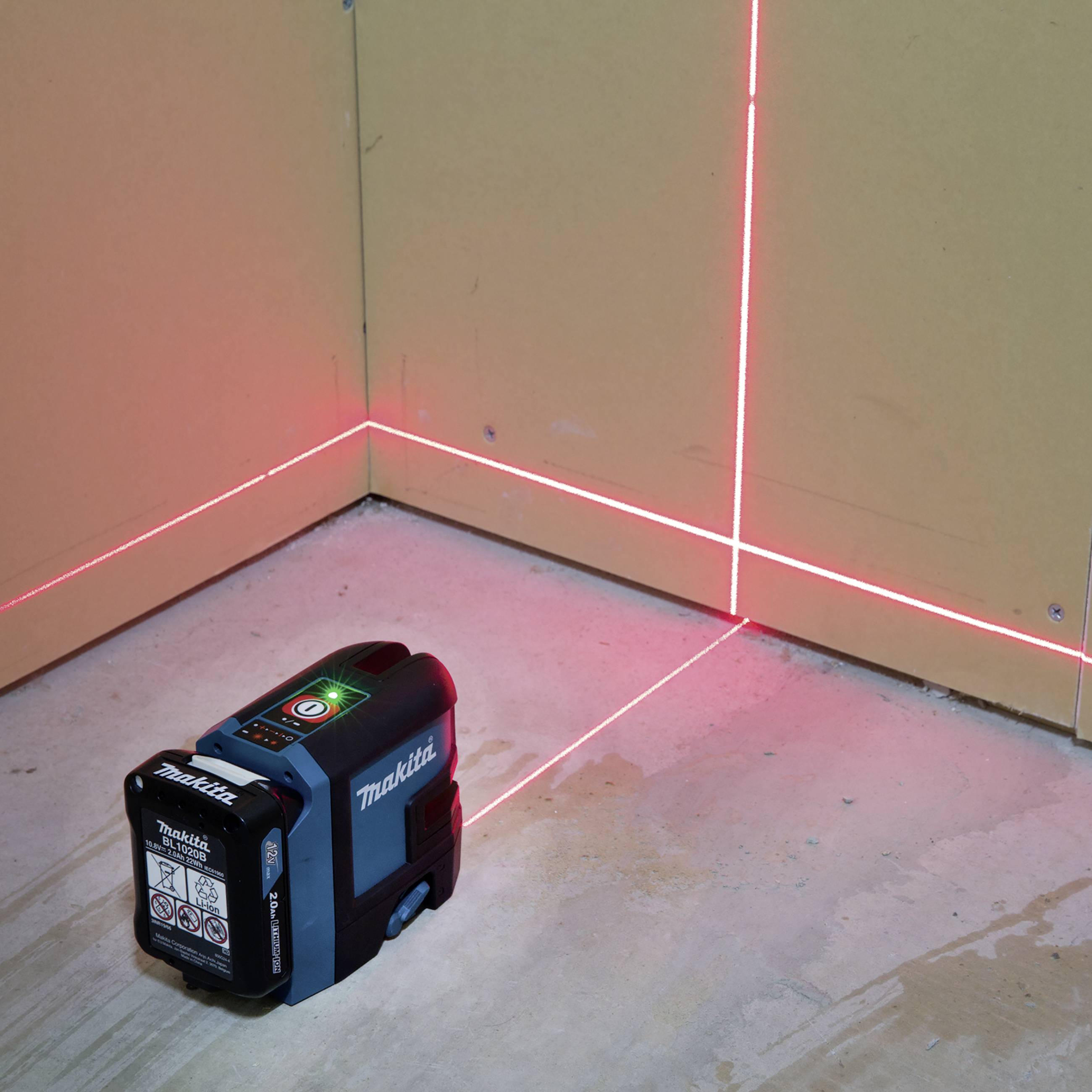 Un nivellement laser vert projette des lignes rouges précises sur les murs et le sol d'une pièce pour faciliter l'alignement.