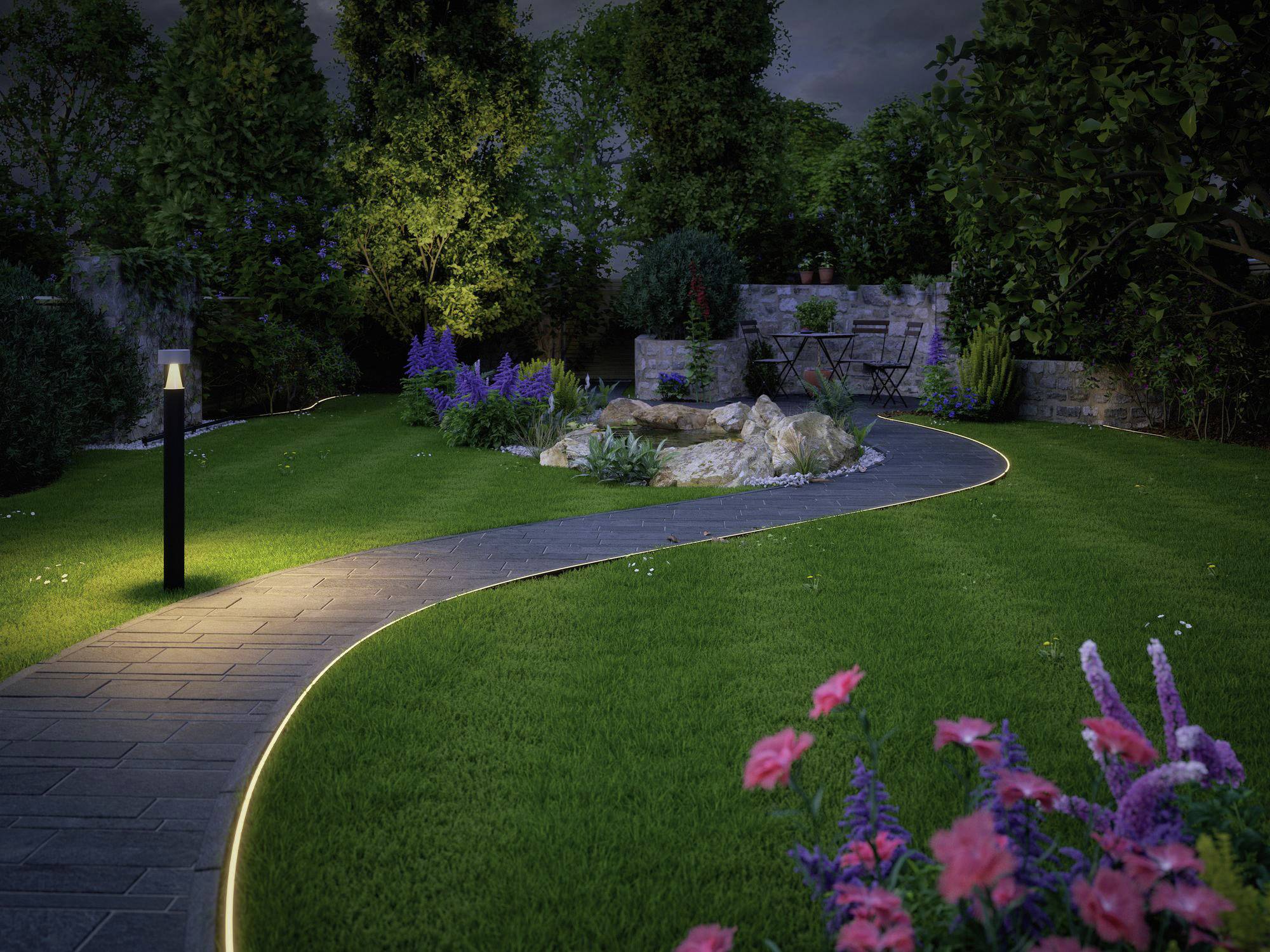 Un jardin entretenu la nuit avec un chemin éclairé et sinueux, des parterres de fleurs et un espace de repos à l'arrière-plan.