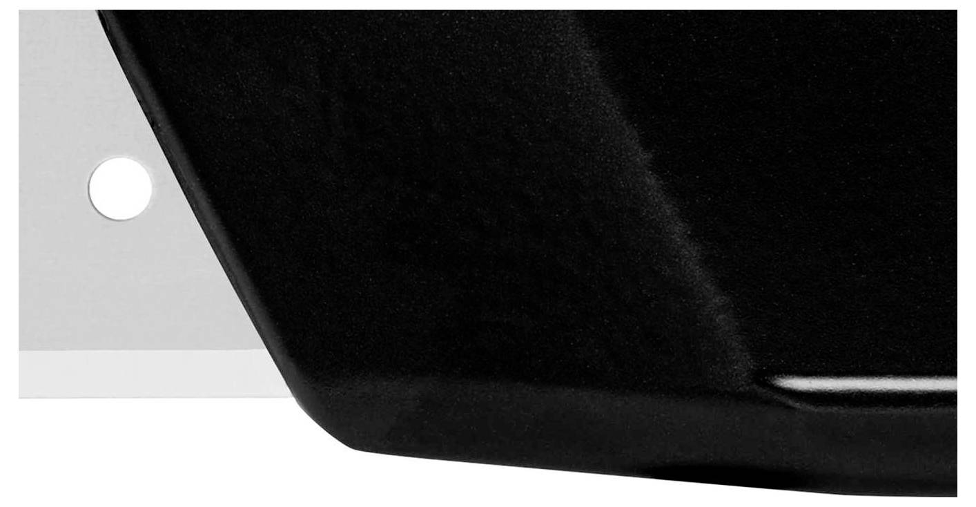 Surface noire à texture lisse et brillante, un élément blanc avec un petit trou à gauche.
