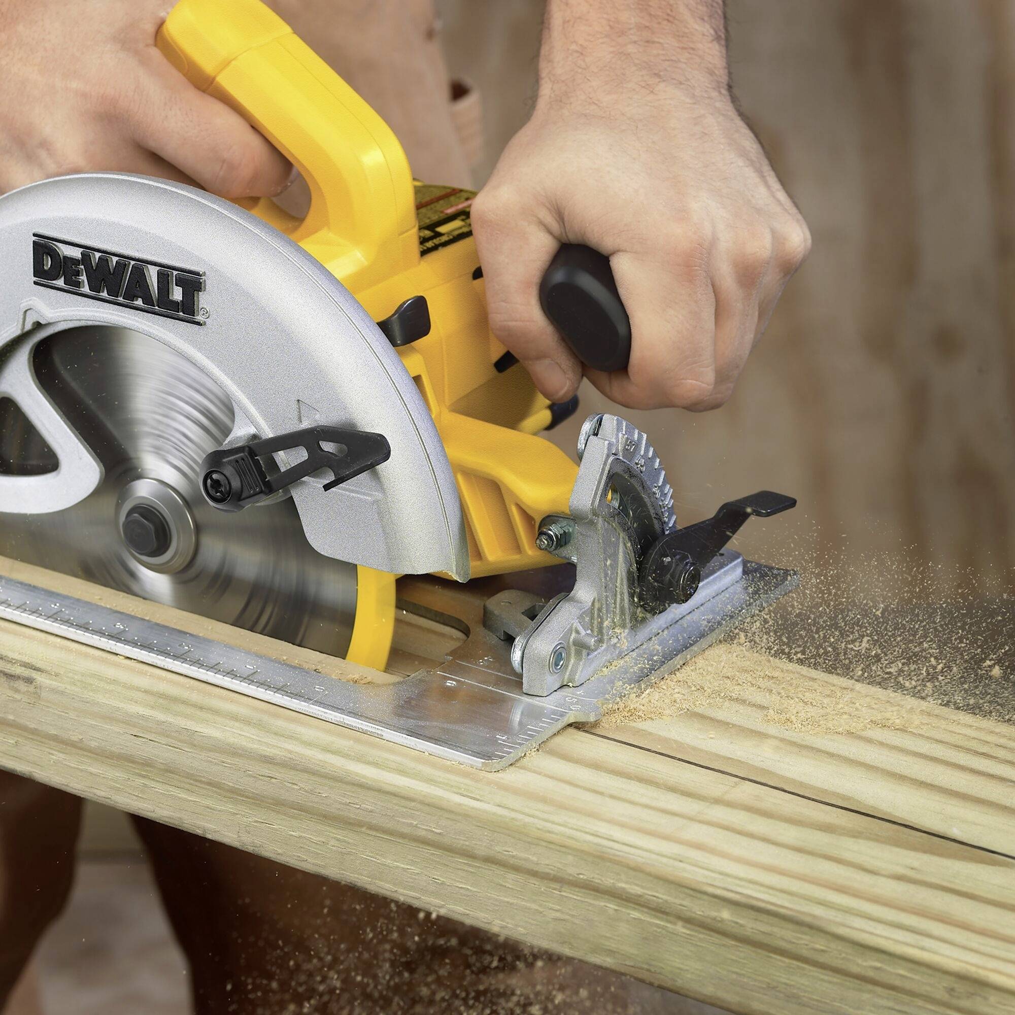 Une personne utilise une scie circulaire jaune pour couper une planche en bois. Des copeaux de sciure volent dans tous les sens ; la scie porte l'inscription « DEWALT ».