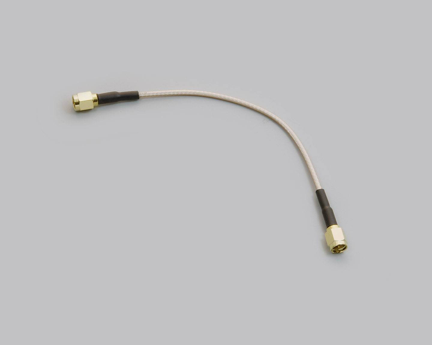 Un câble coaxial court et flexible, doté de connecteurs dorés aux deux extrémités, utilisé pour connecter des composants électroniques.