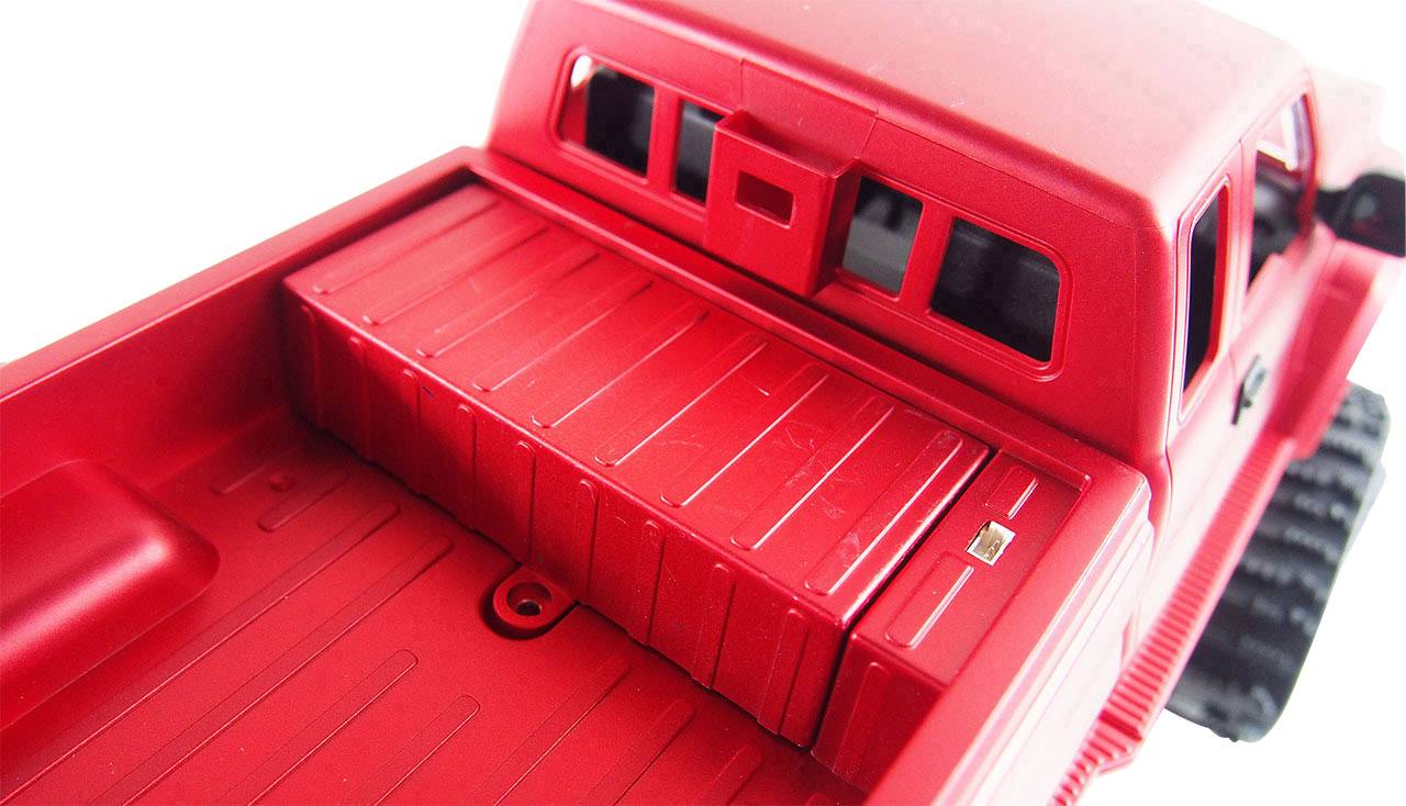 Voiture miniature rouge photographiée de dos, montrant la surface de chargement et la vue arrière, sans marquages ou particularités spécifiques.