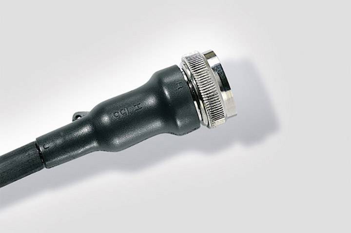 Gros plan d'un connecteur de câble coaxial sur un fond gris, montrant un câble noir avec une fiche métallique.