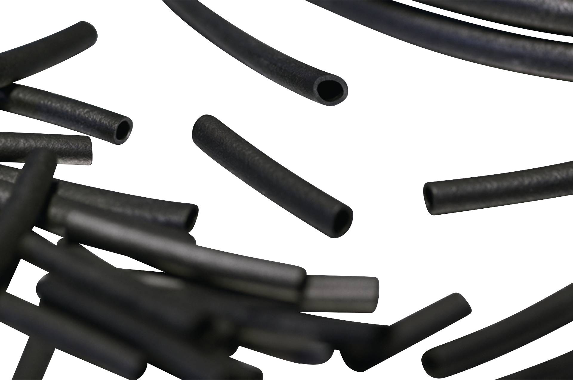 Plusieurs tuyaux en plastique noir de différentes longueurs, disposés de manière aléatoire sur un fond blanc.