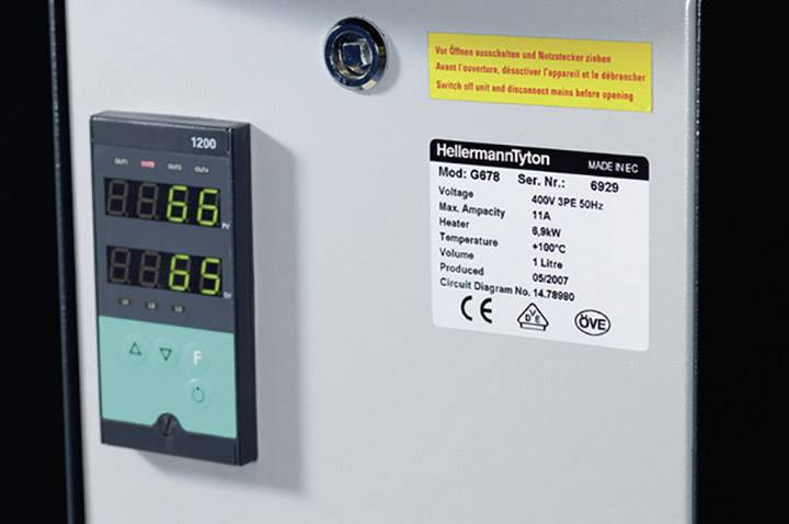 Panneau de commande électrique avec deux affichages numériques. En haut, il est inscrit « Éteindre avant d'ouvrir ! ». Un autocollant indique les caractéristiques techniques de l'appareil.