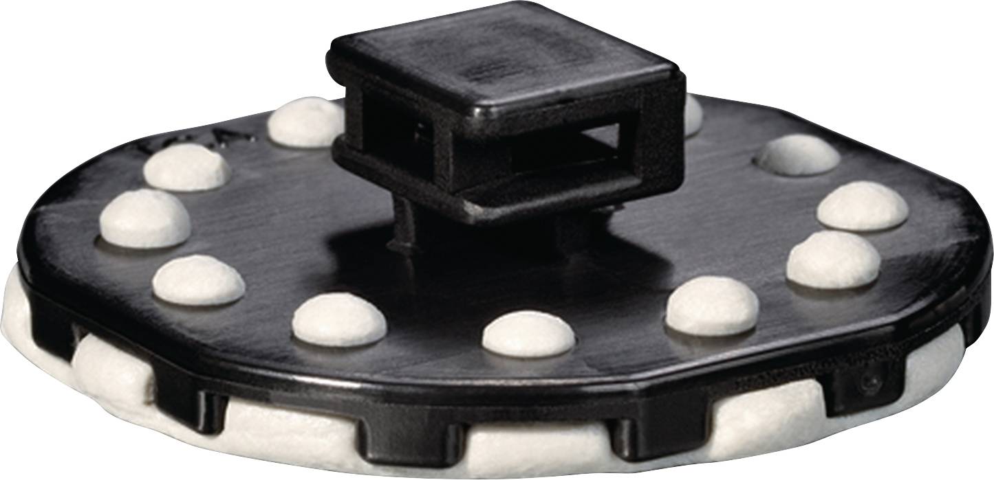 Un objet noir et rond avec plusieurs coussins blancs et ronds posés dessus. Une structure rectangulaire surélevée se trouve au-dessus.