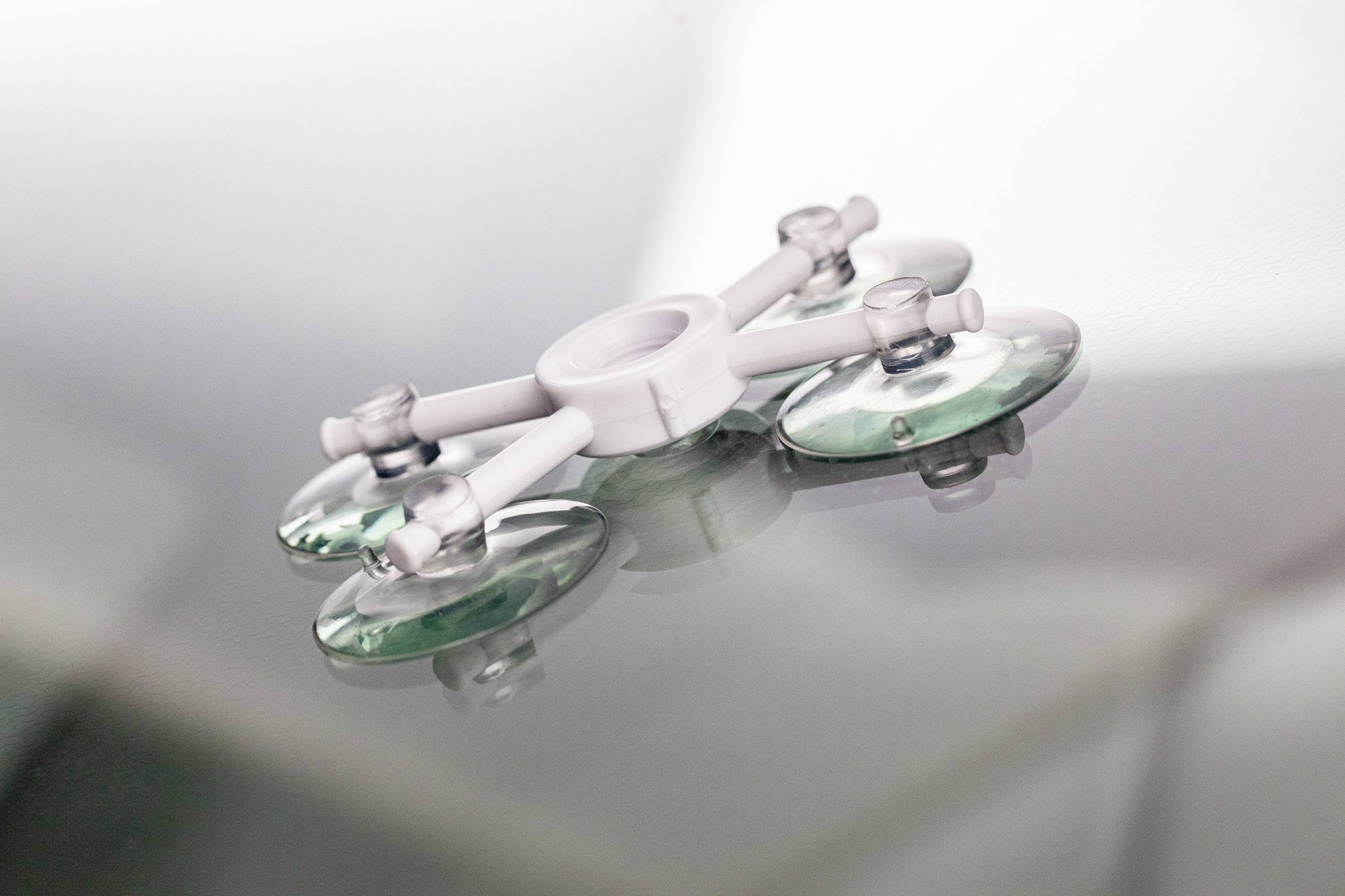 Un appareil blanc à ventouses avec quatre ventouses vertes est posé sur une surface lisse et réfléchissante.