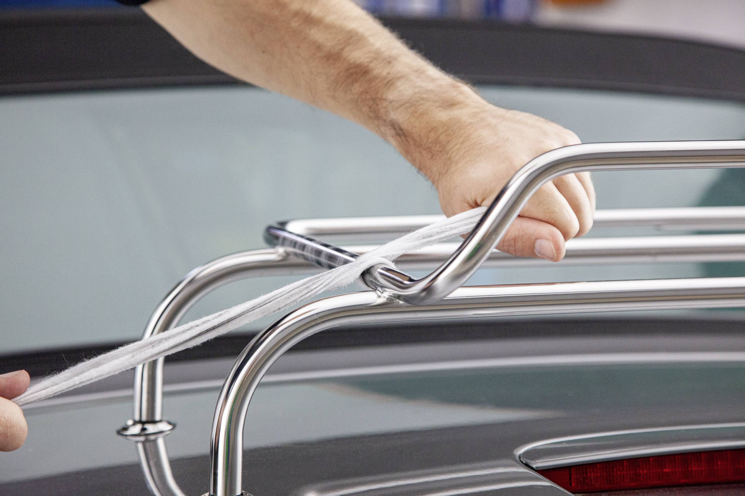 Une personne attache une corde à un porte-bagages argenté sur le toit d'une voiture.