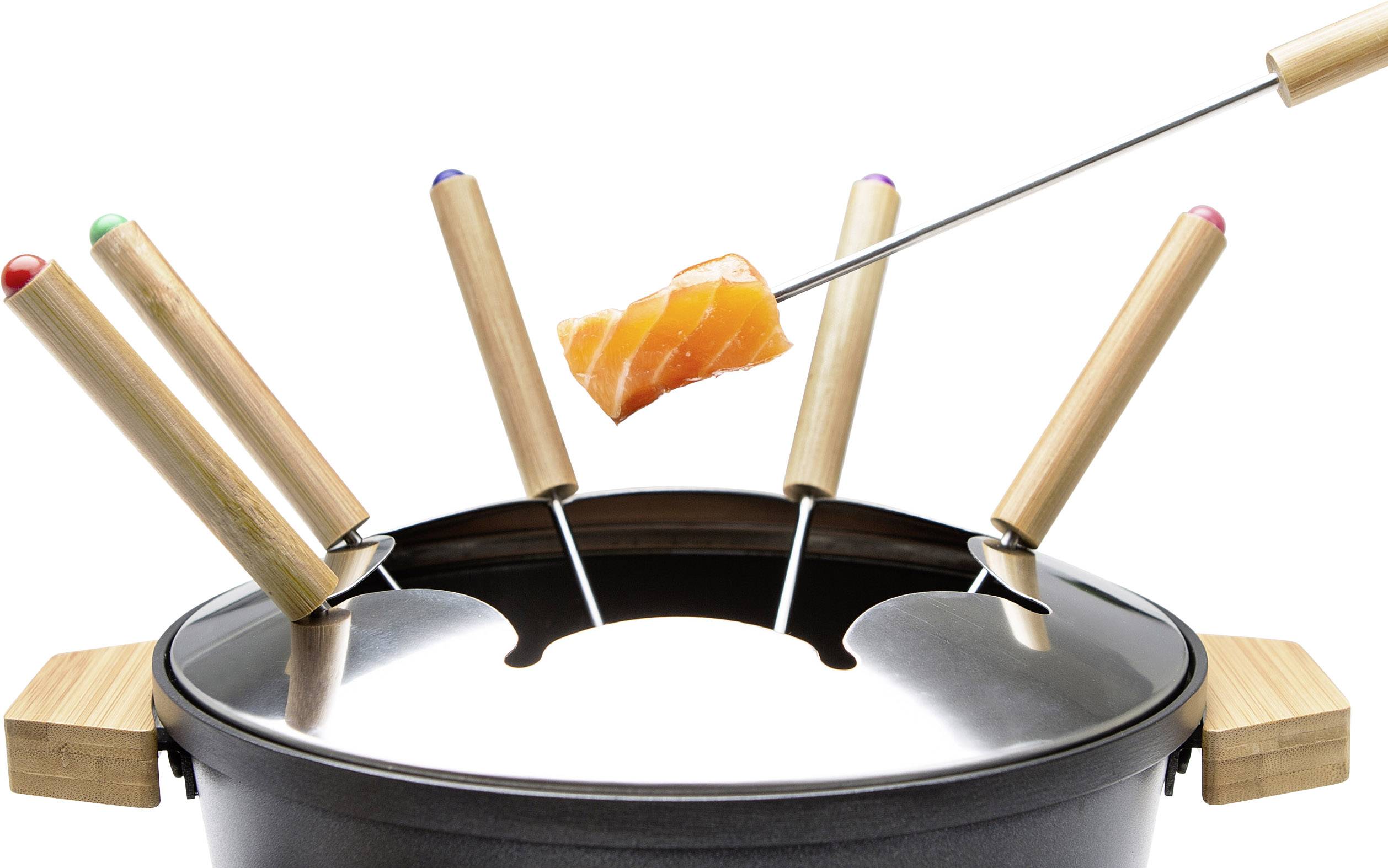 Ensemble à fondue avec quatre fourchettes, l'une tenant un morceau de saumon au-dessus de la casserole. Les fourchettes ont des extrémités colorées. Scène de plat principal.