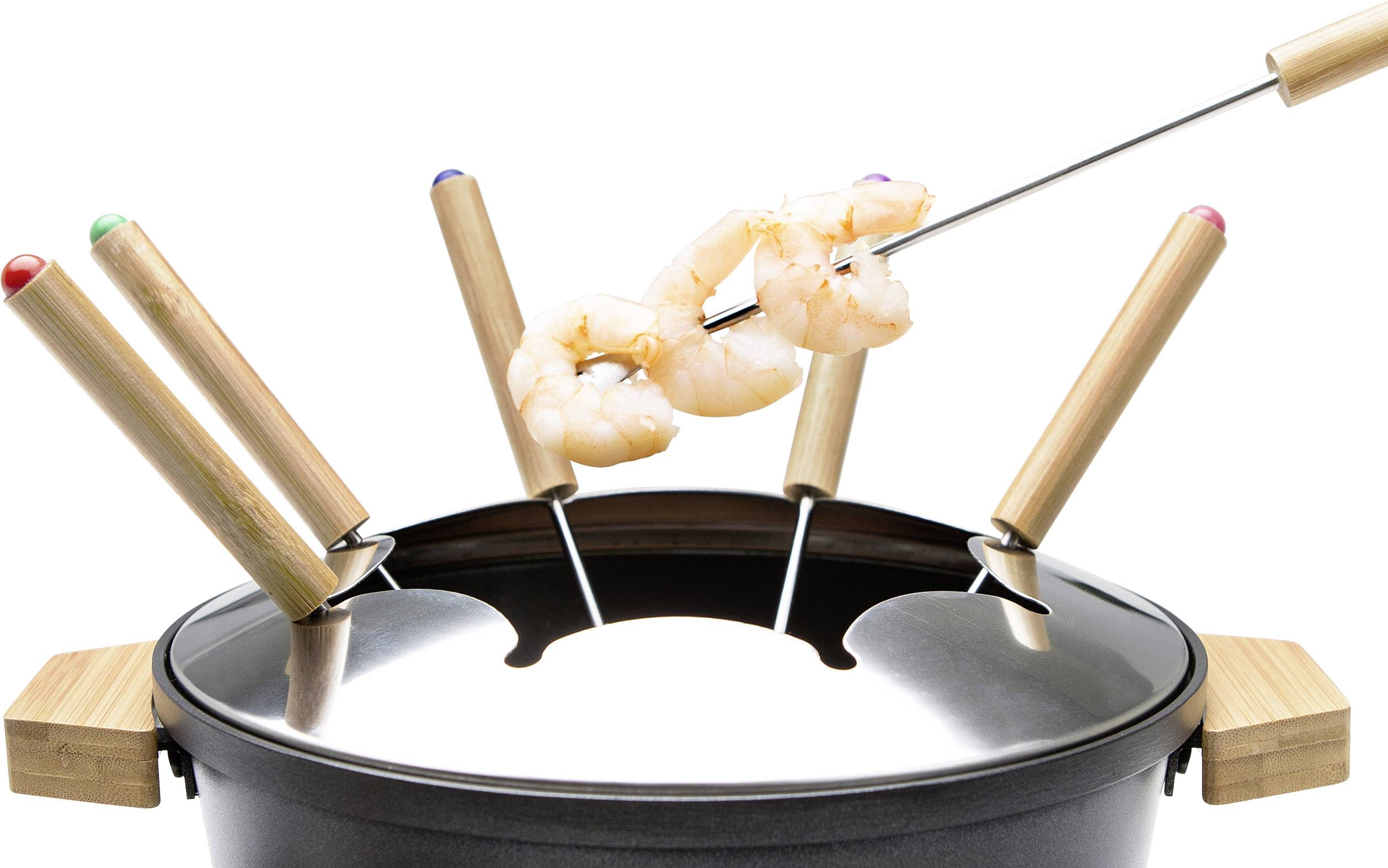 Pot à fondue avec quatre fourchettes marquées de différentes couleurs, une fourchette tenant deux crevettes au-dessus du pot.